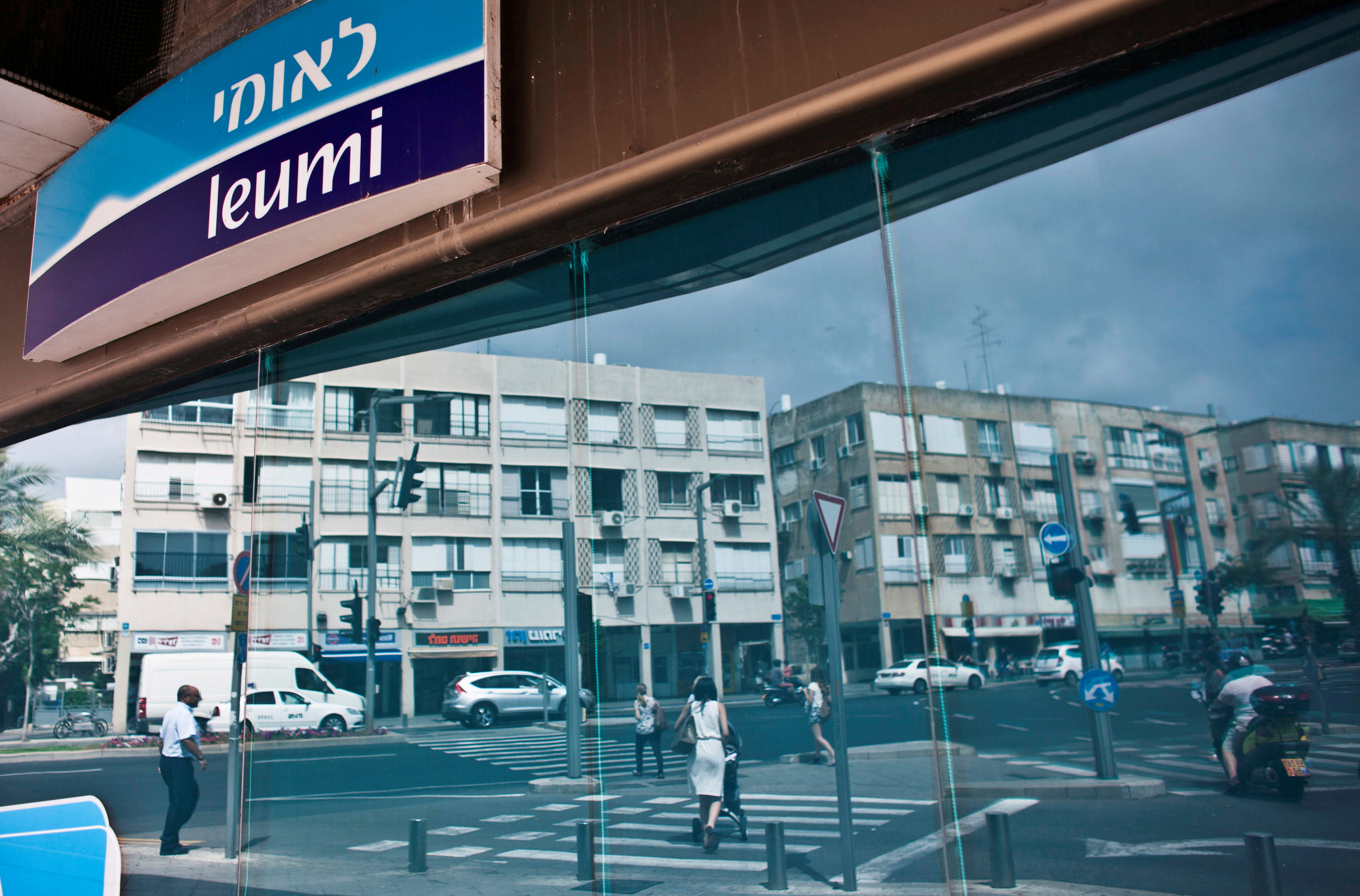 Pedestrians are reflected in windows of Bank Leumi branch in Tel Aviv