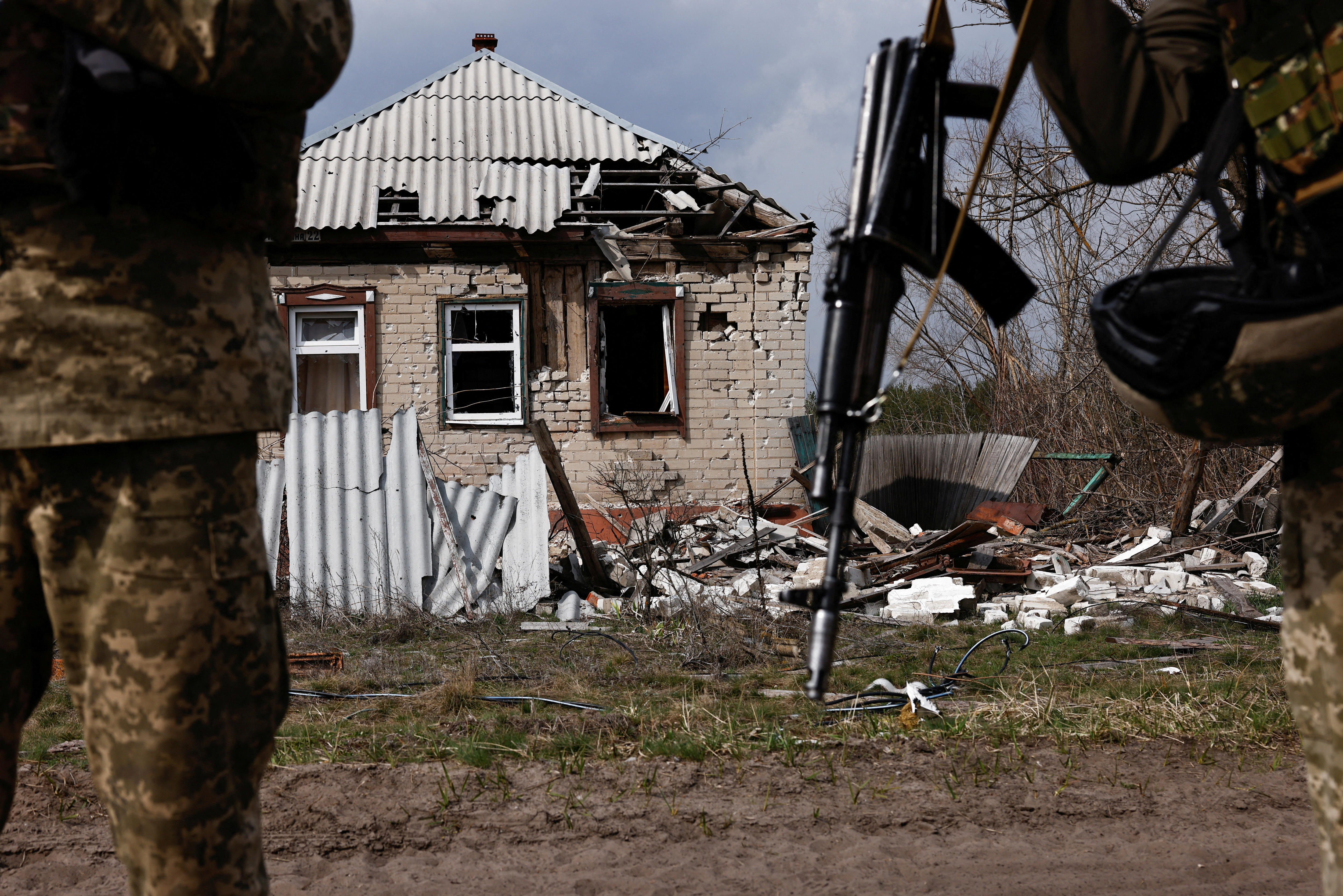 Ukrainian servicemen stand next to a destroyed building near the frontline town of Kreminna