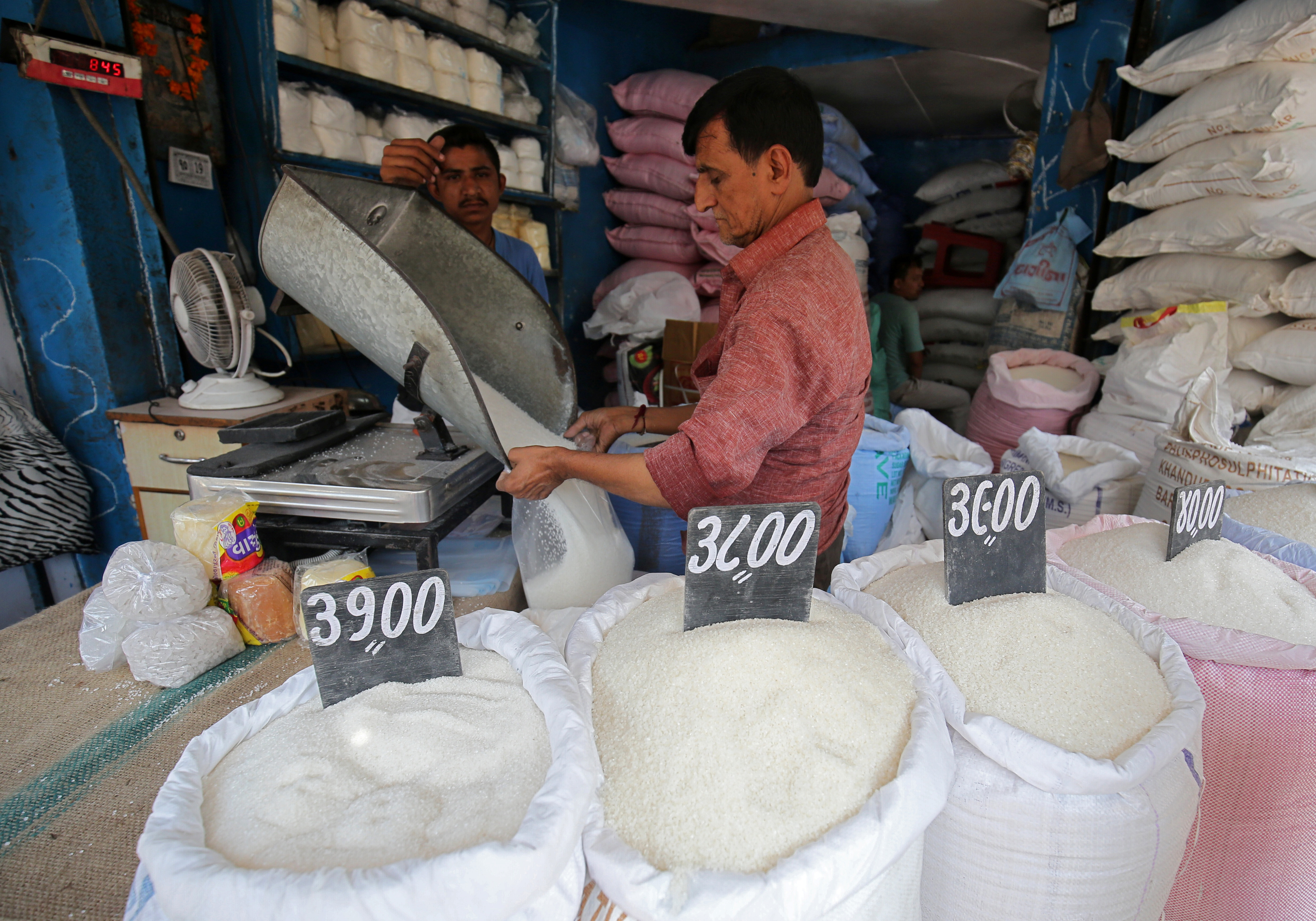 A man packs sugar for sale inside a shop at a marketplace in Ahmedabad