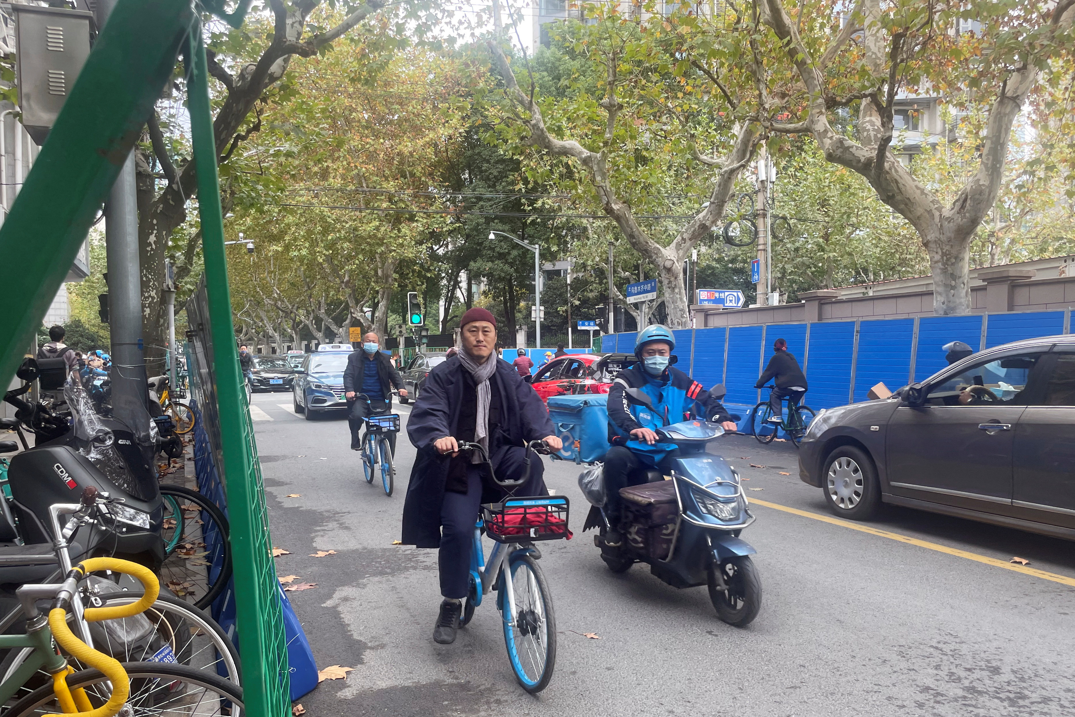 People ride past barriers set up along a road in Shanghai