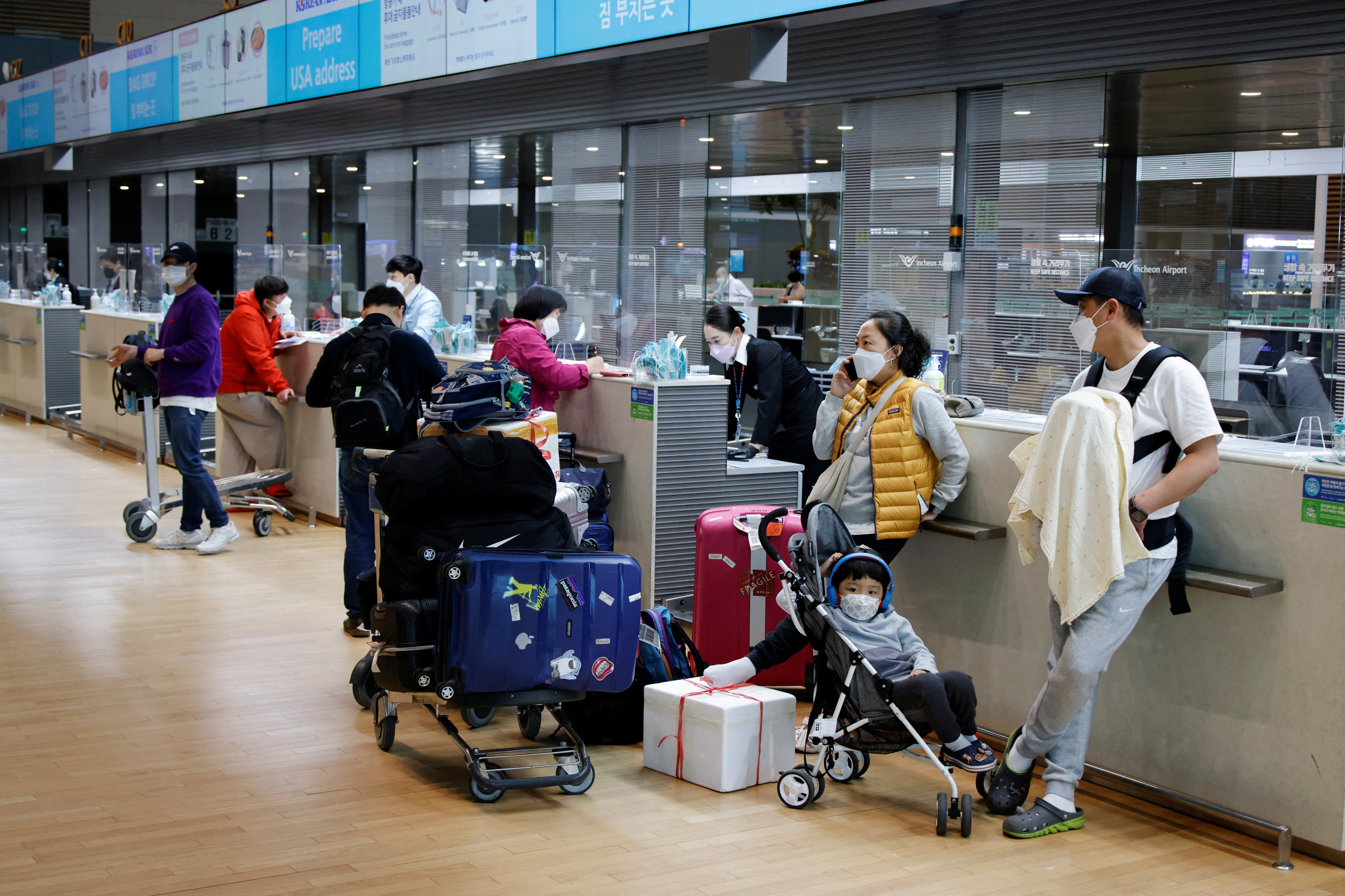 People wearing face masks to prevent from contracting the coronavirus disease (COVID-19) wait to check in at Incheon International Airport, in Incheon, South Korea