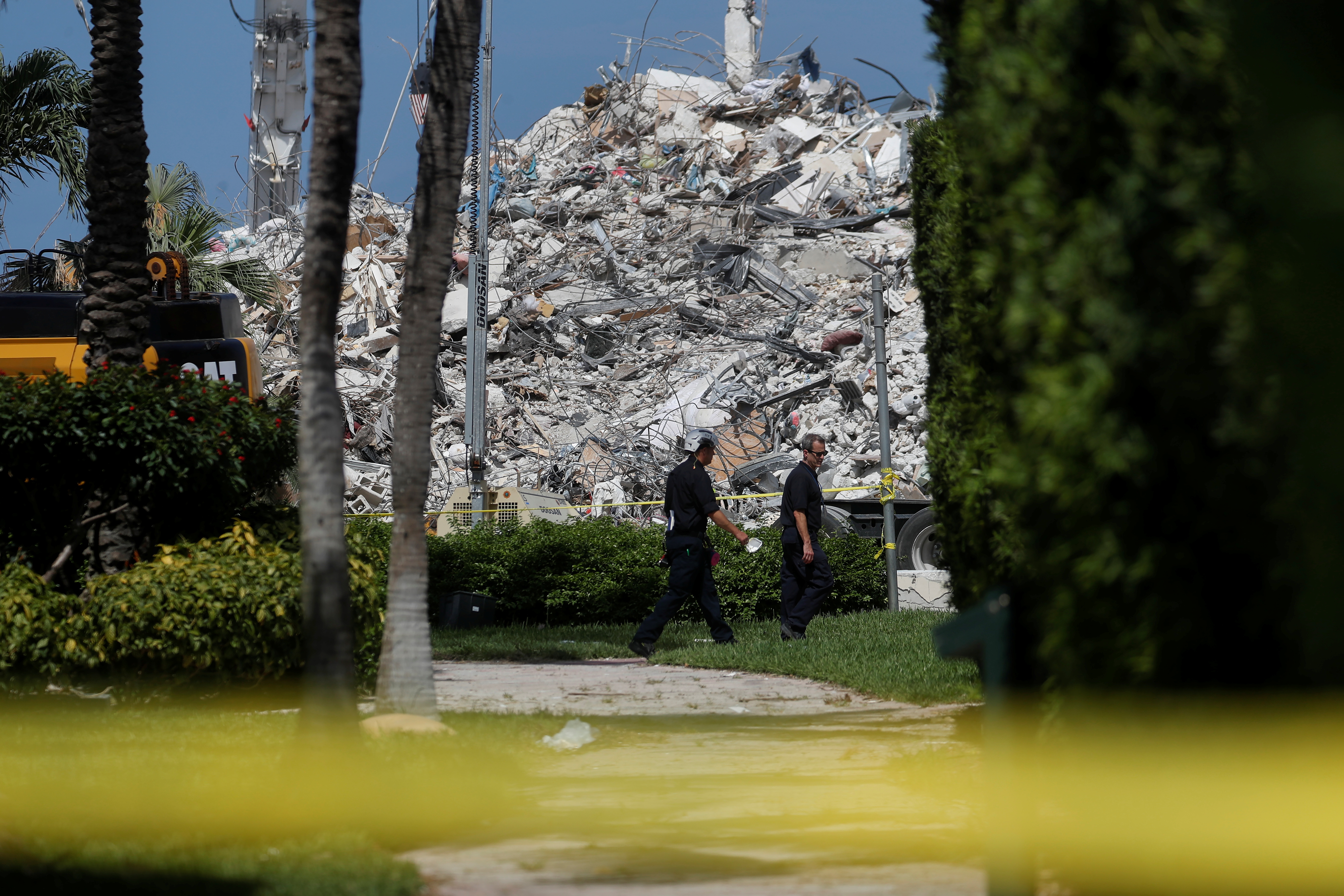 Search teams walk by the remains of the Surfside's Champlain Towers South condominium in Miami, Florida