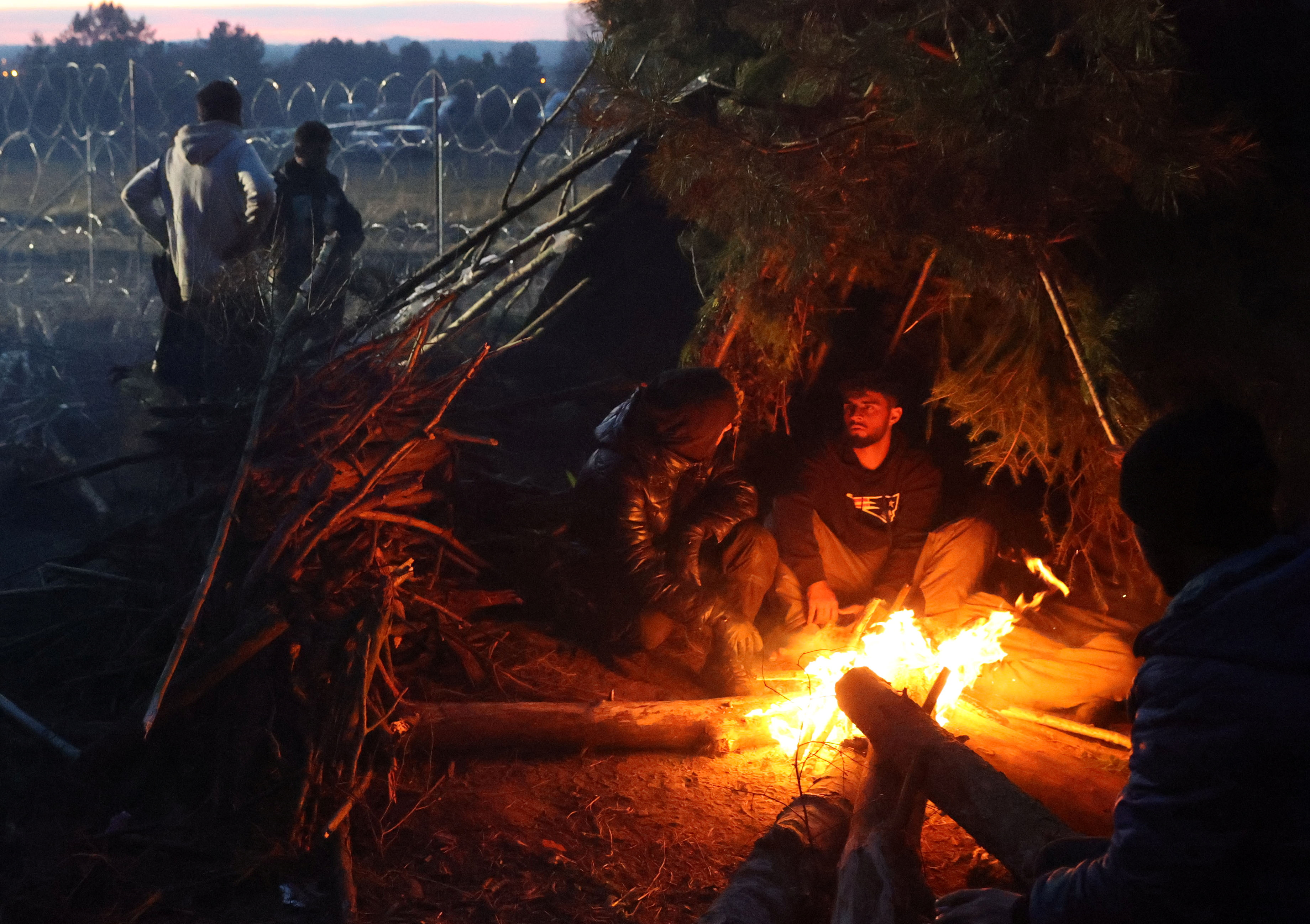 Migrants gather near a fire on the Belarusian-Polish border in the Grodno region