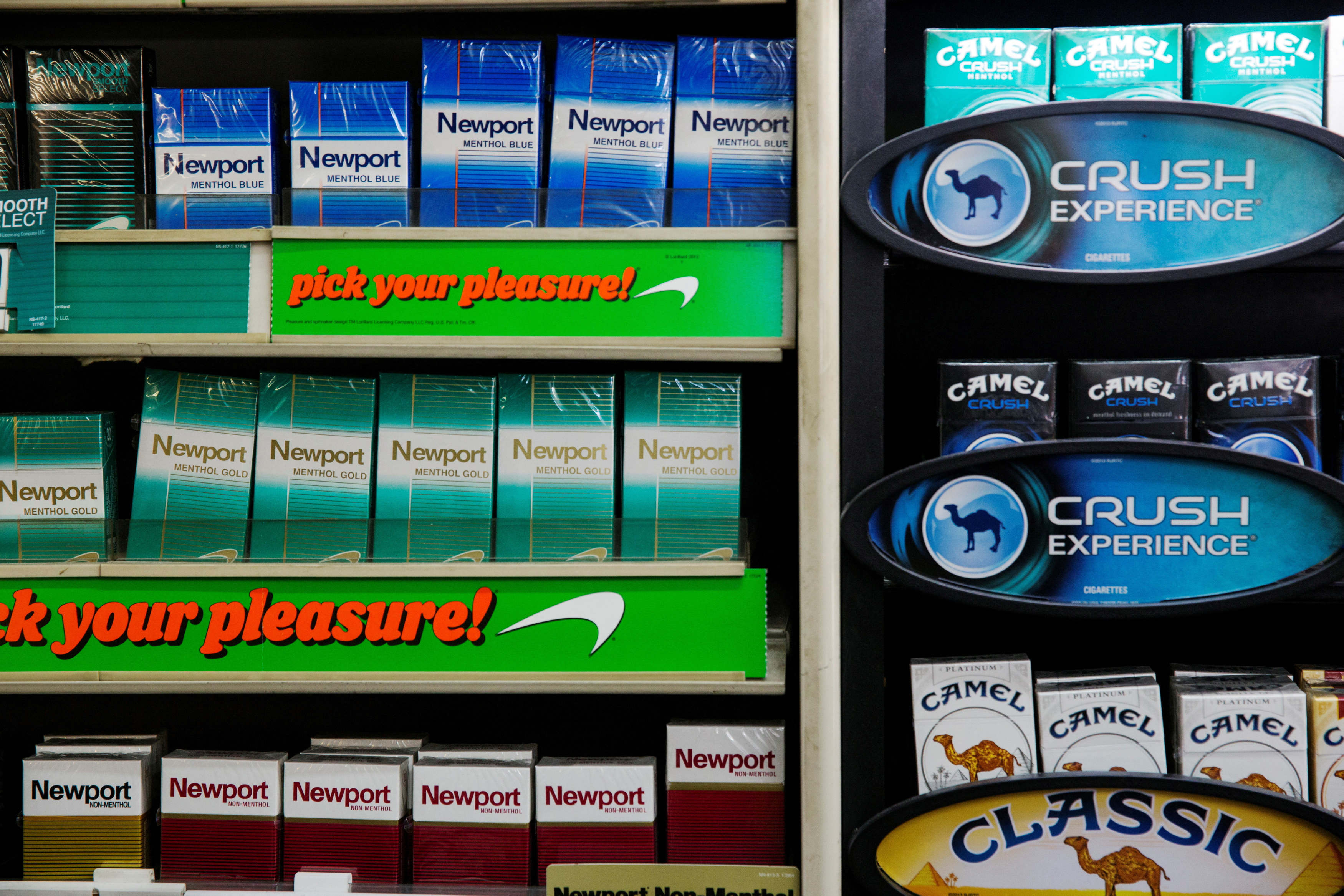 Newport and Camel cigarettes are stacked on a shelf inside a tobacco store in New York