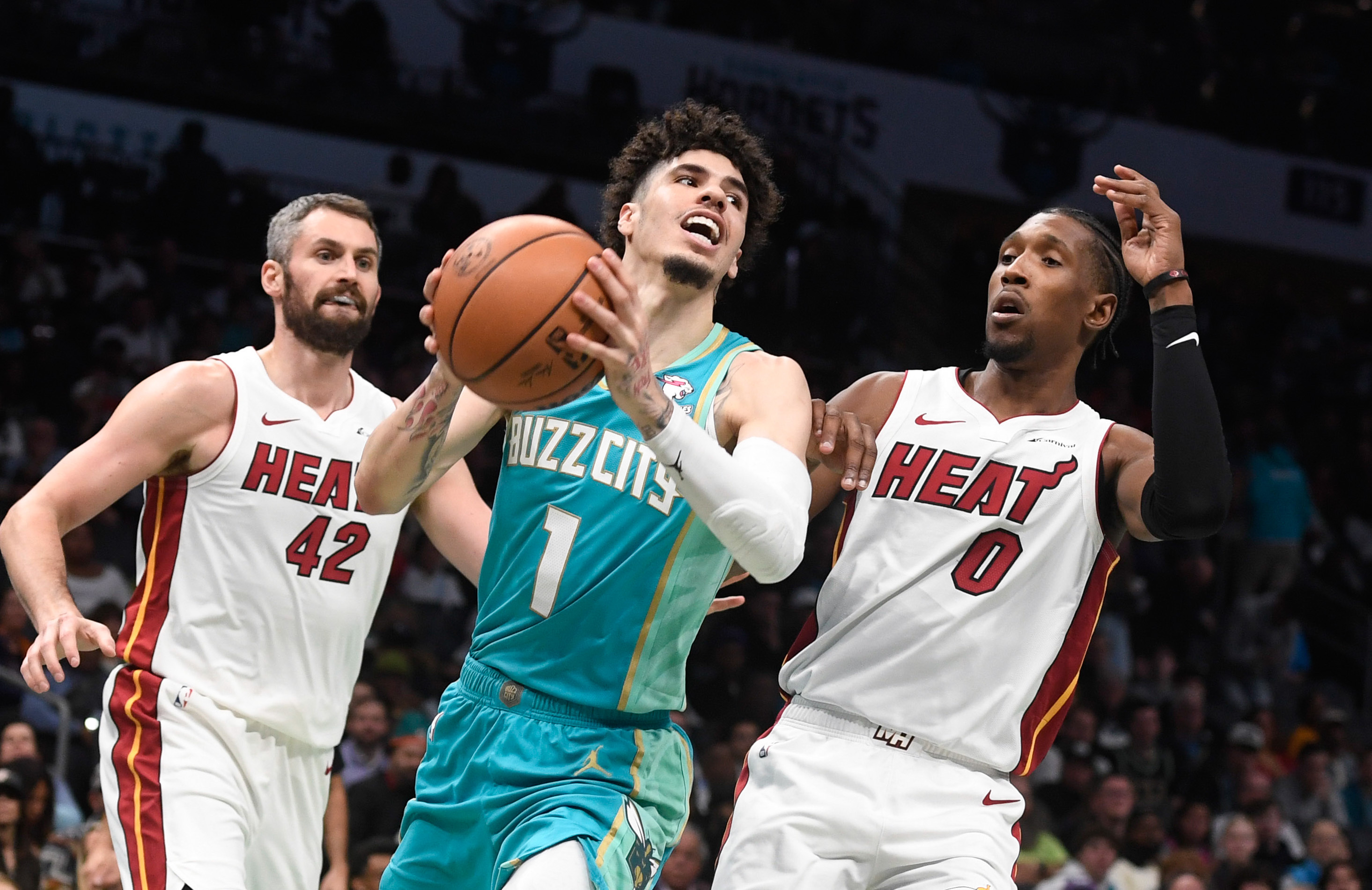 Charlotte Hornets guard LaMelo Ball (2) and Miami Heat forward Jimmy Butler  (22) chase after a loose ball with his shoes displayed during the second  half at the Spectrum Center.