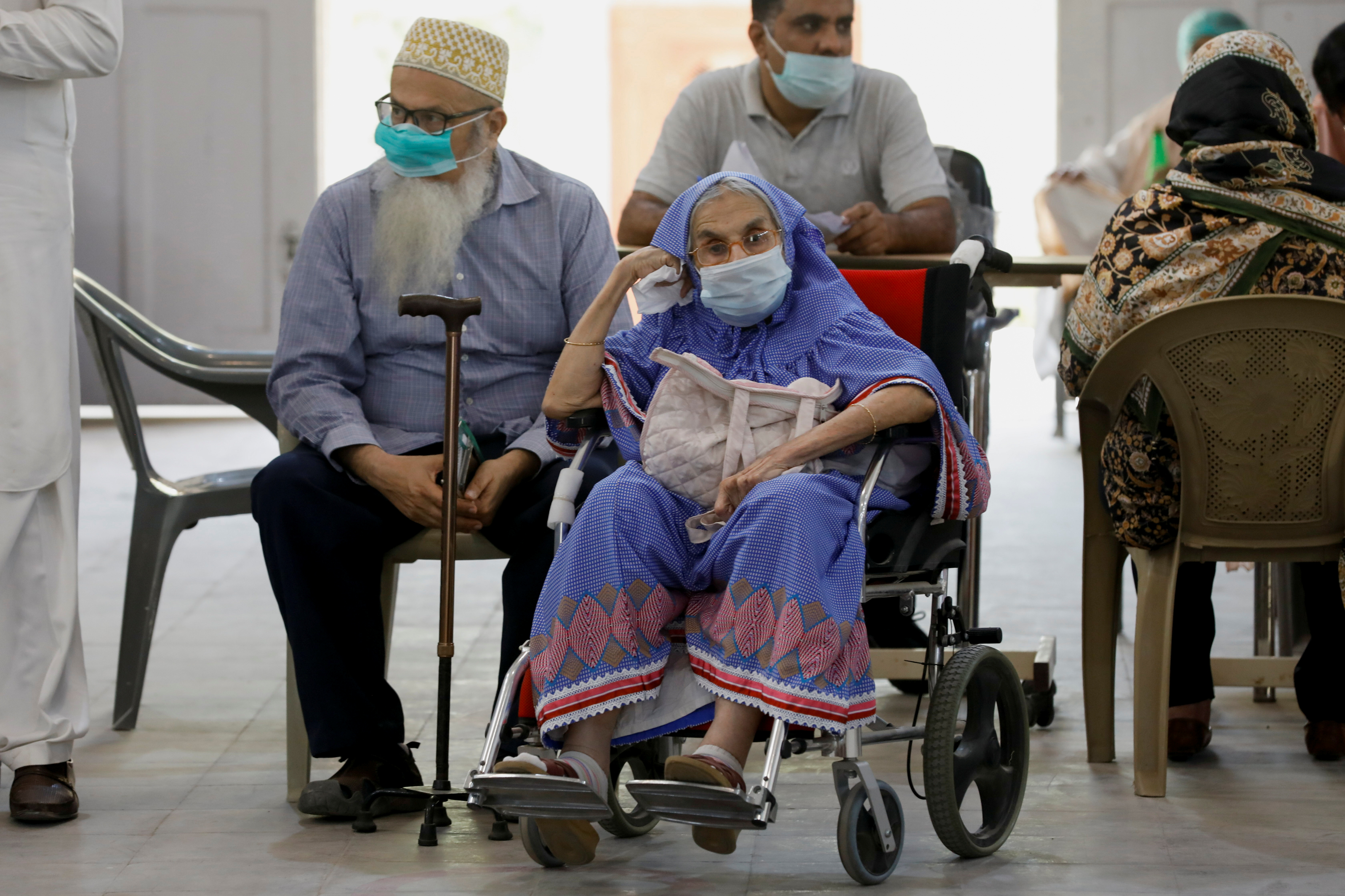 Residents wait for their coronavirus disease (COVID-19) vaccine doses, at a vaccination center in Karachi,