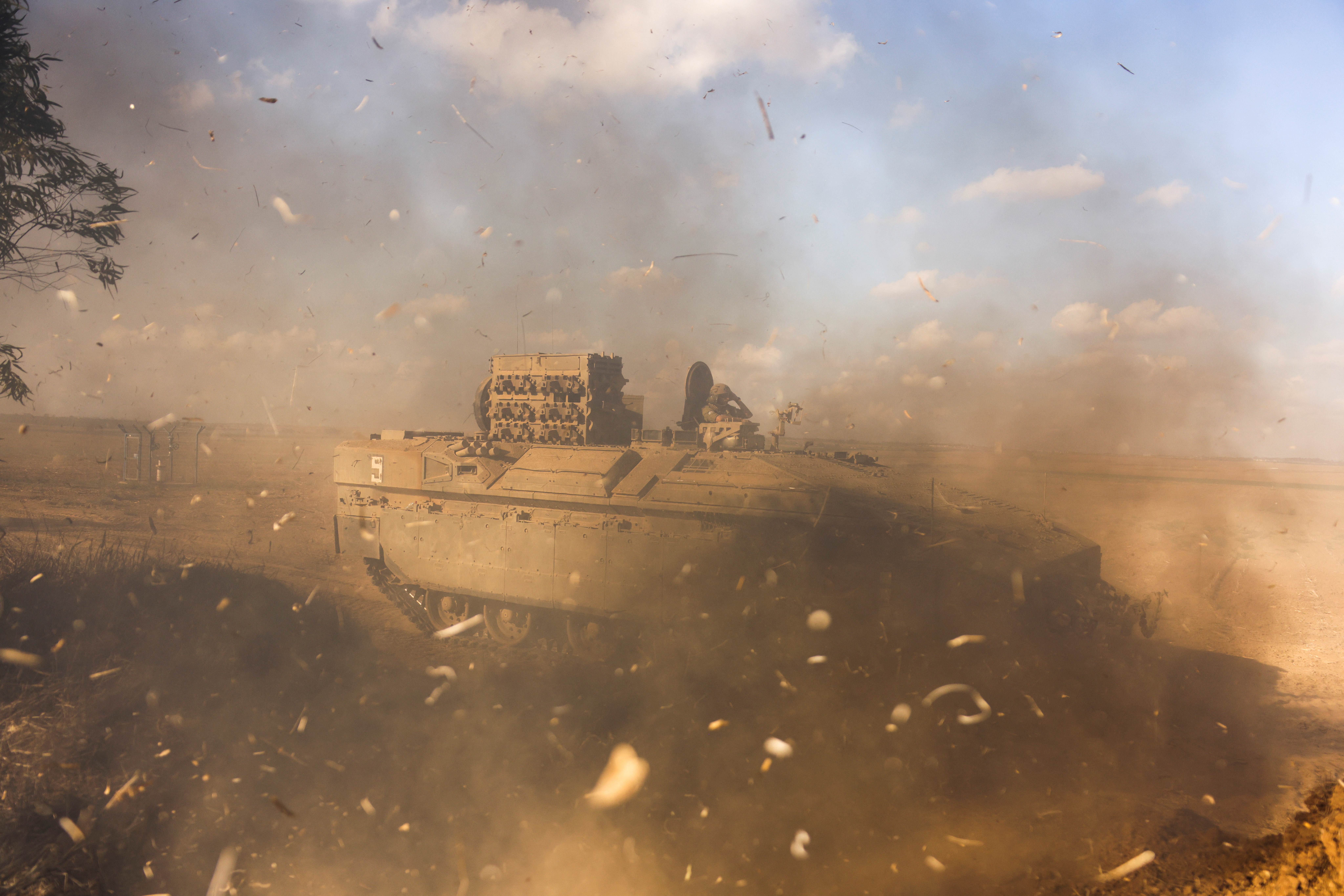 An Israeli Armoured Personnel Carrier (APC) is obscured as it whips up dust near Israel's border with the Gaza Strip, in southern Israel
