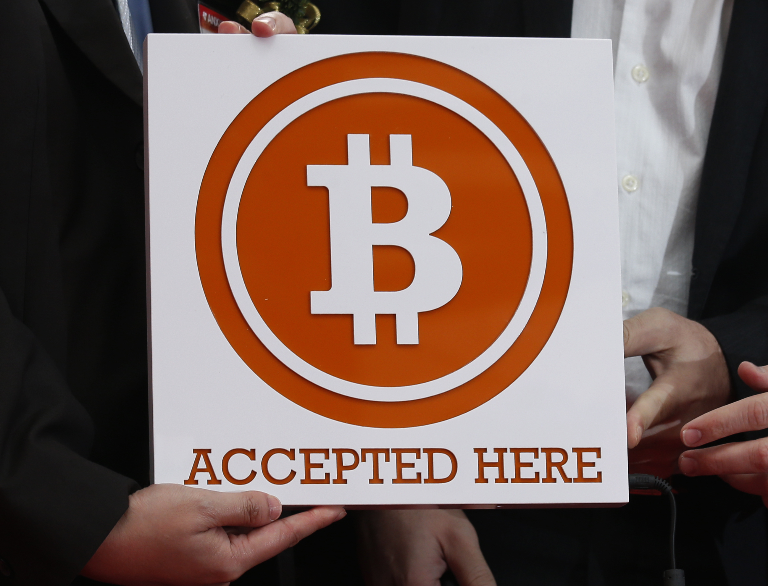 Bitcoin sign is held outside Hong Kong's first bitcoin retail store during its opening, in Hong Kong