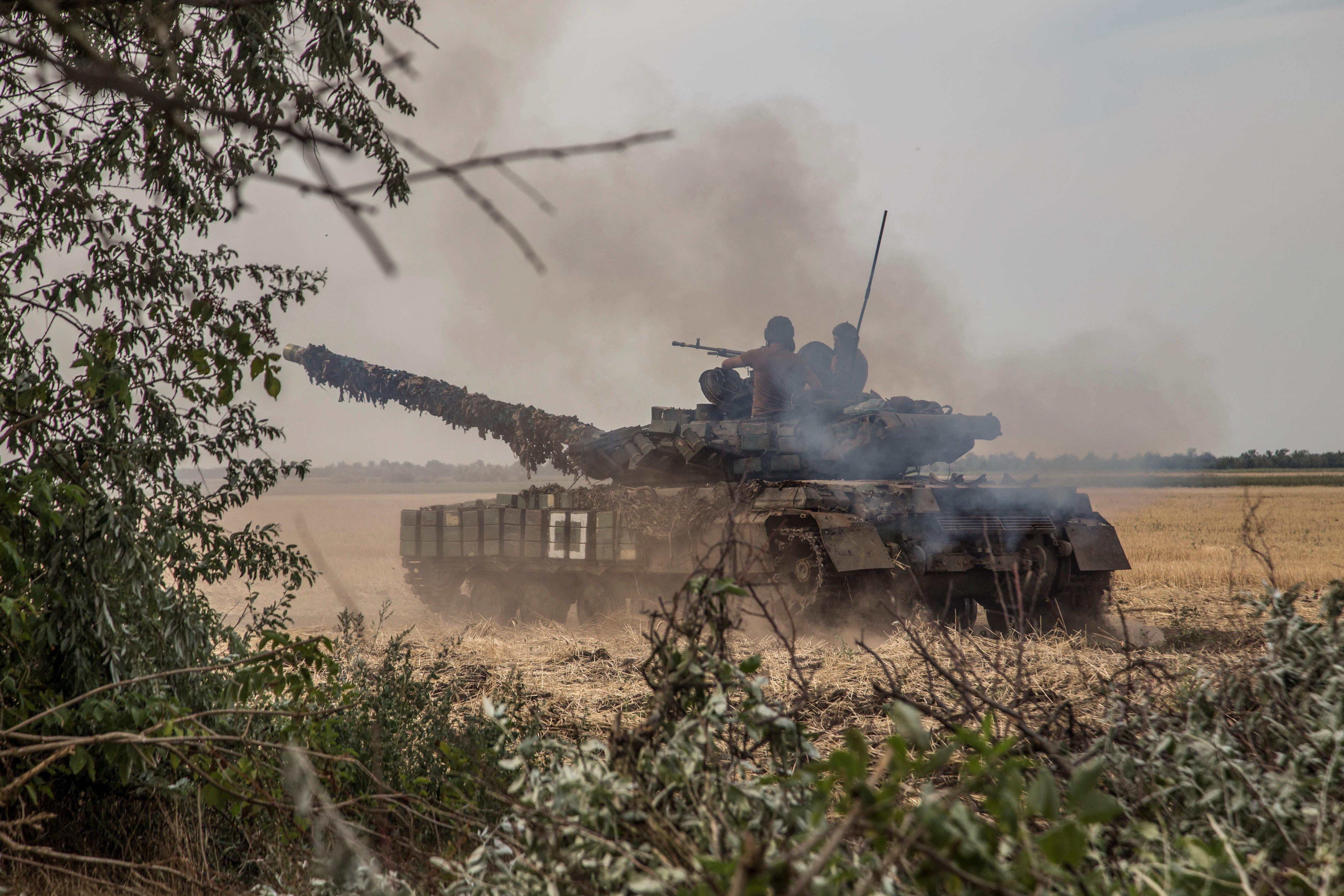 Ukrainian servicemen ride atop a tank near a front line in Mykolaiv region