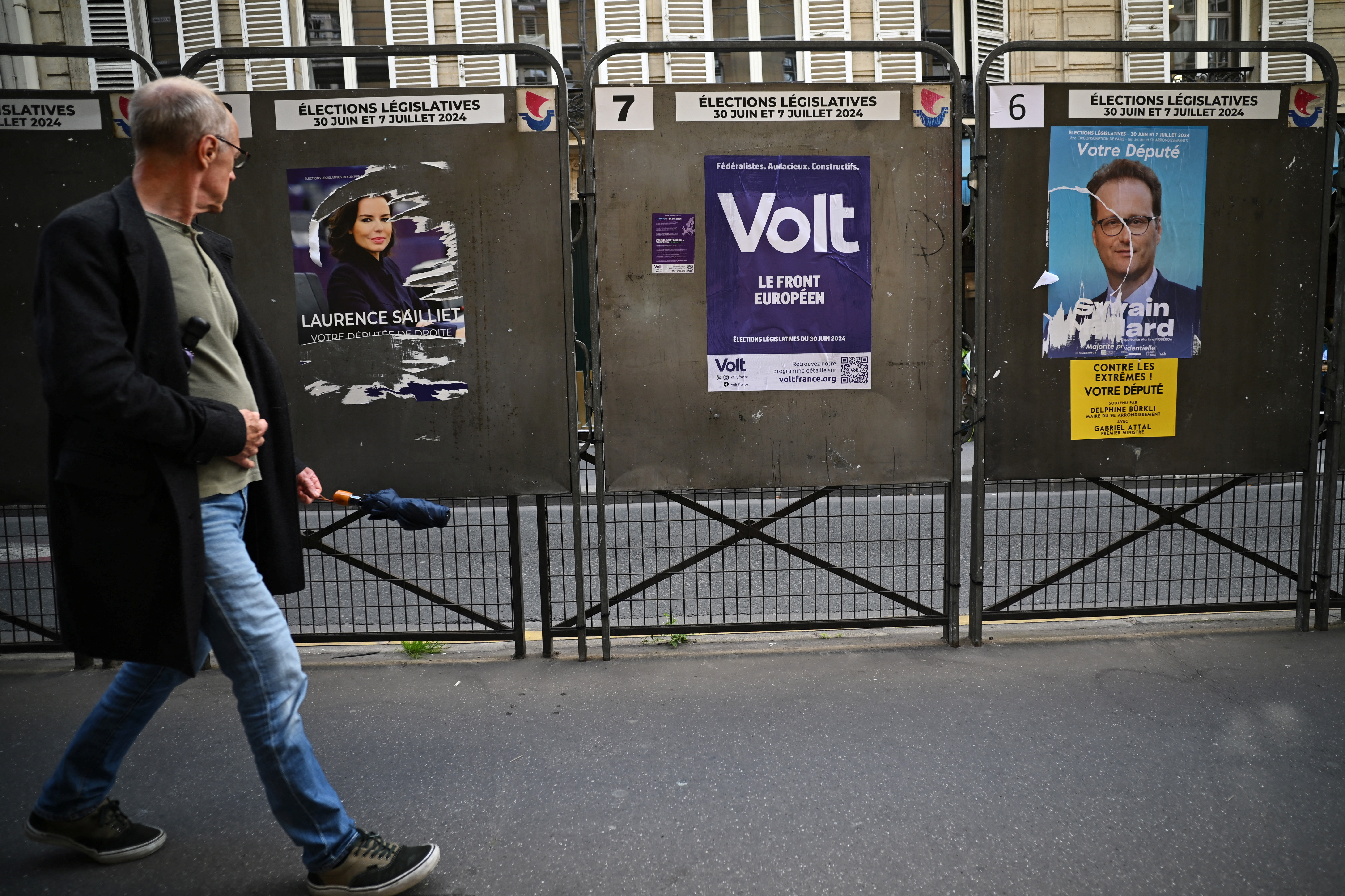 A man walks past election posters ahead of the French parliamentary elections in Paris