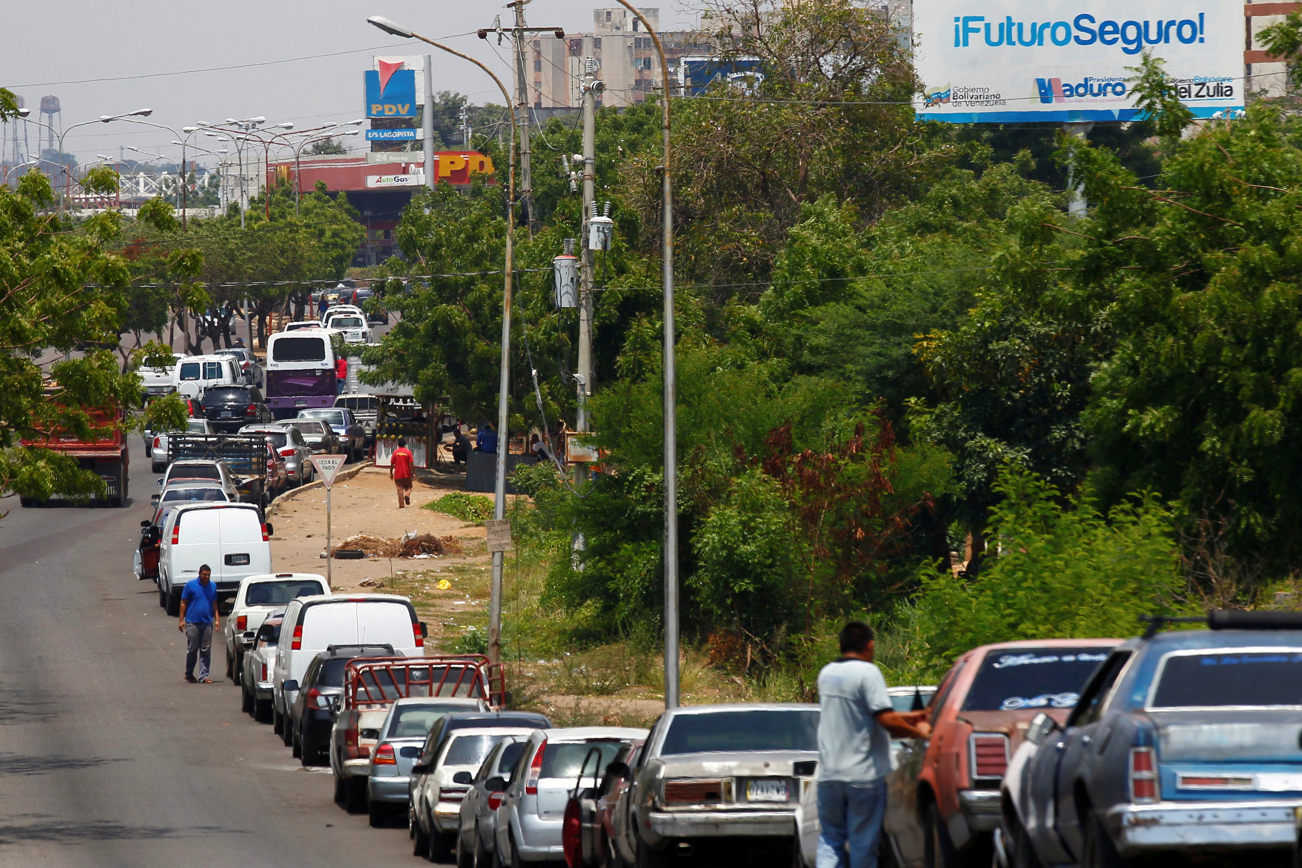 FILE PHOTO: People with vehicles wait in line in an attempt to refuel at a gas station of the state oil company PDVSA in Maracaibo