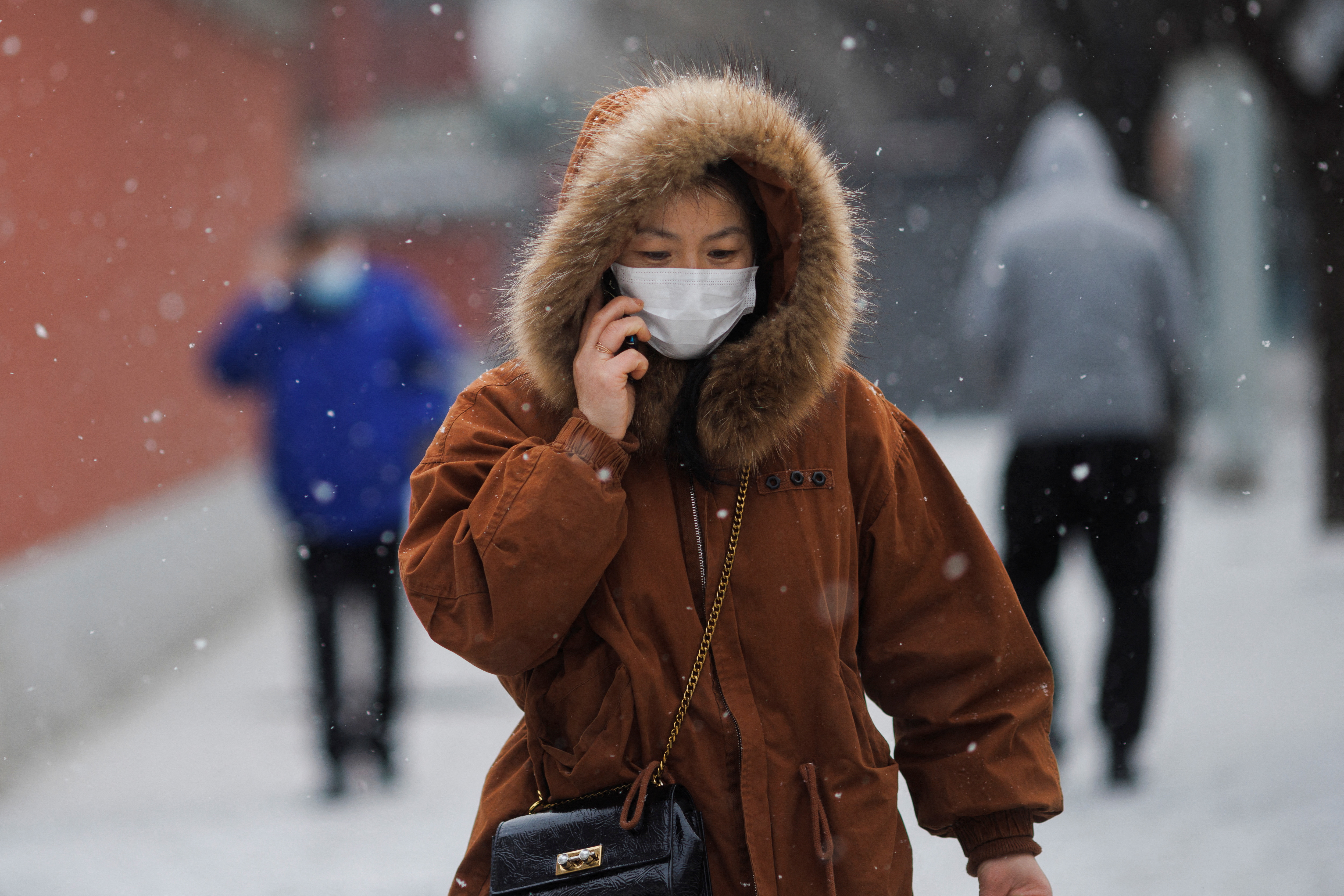 A person wears a face mask while walking on a snowy morning as the coronavirus disease (COVID-19) continues in Beijing, China, January 20, 2022.   REUTERS/Thomas Peter
