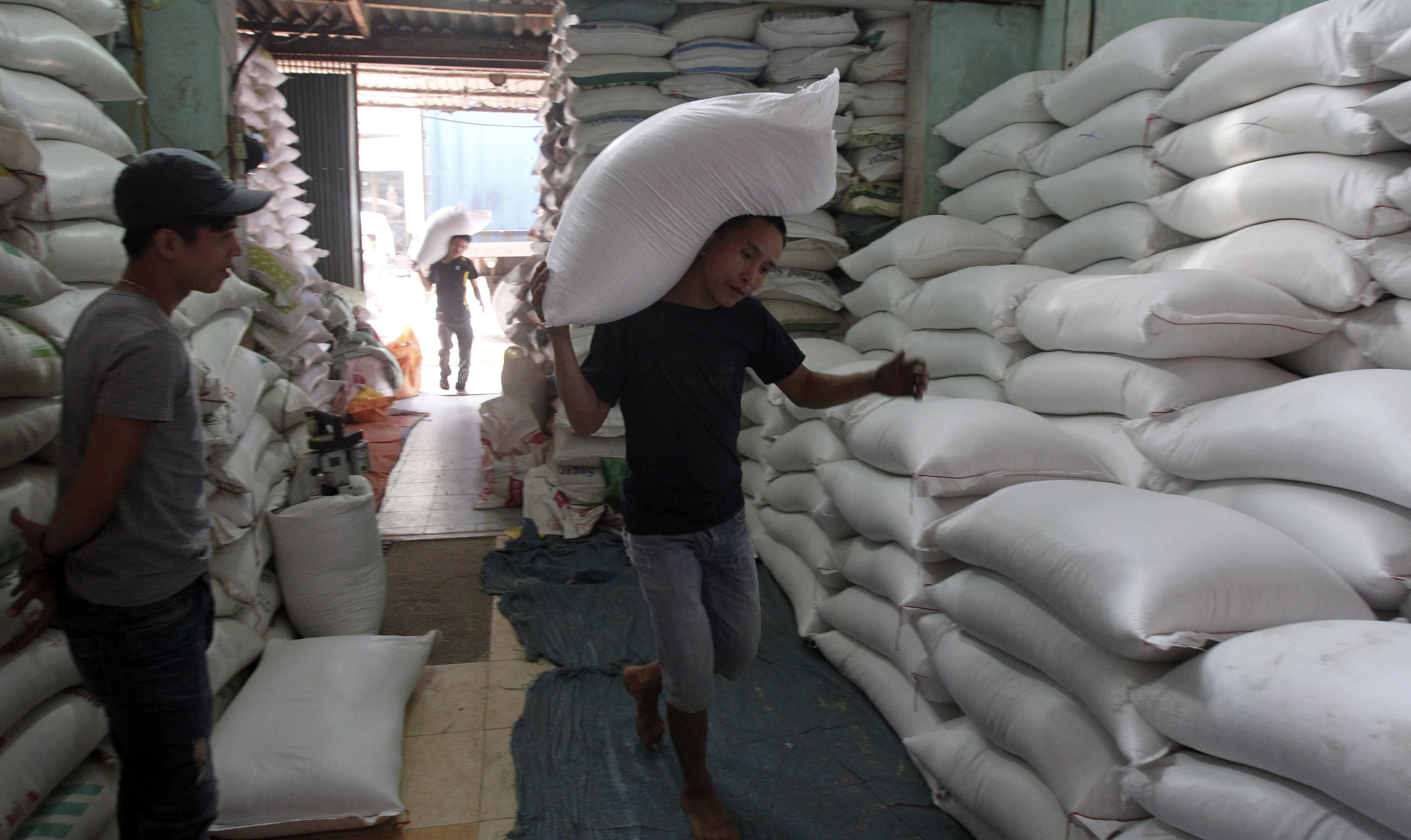 A worker carries a bag of rice to a store outside Hanoi