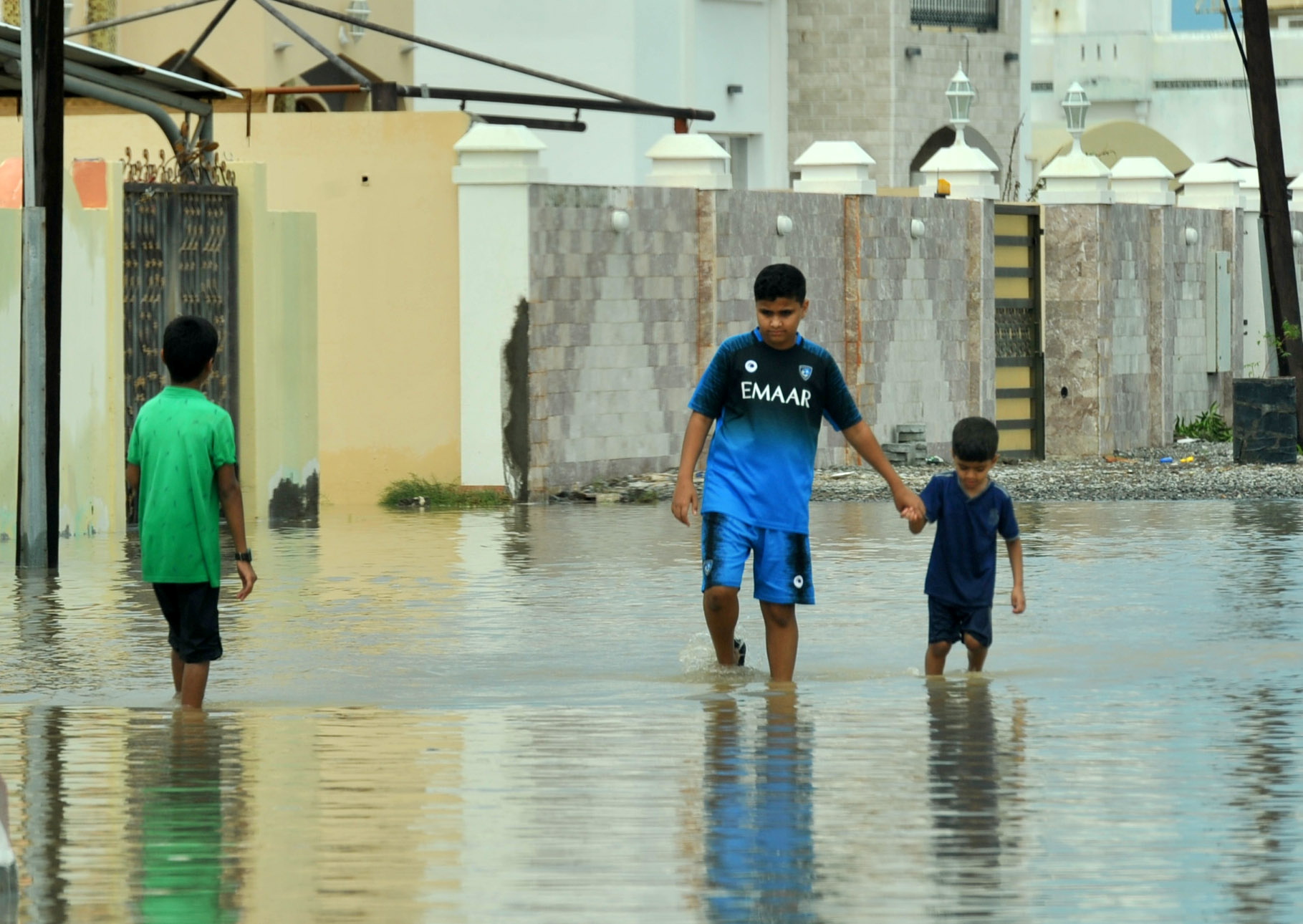 Locals walk in flooded streets caused by Cyclone Shaheen in Al Musanaa