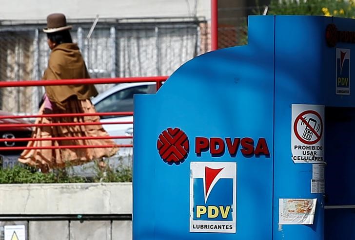 A woman walks next to a closed PDVSA fuel station in La Paz