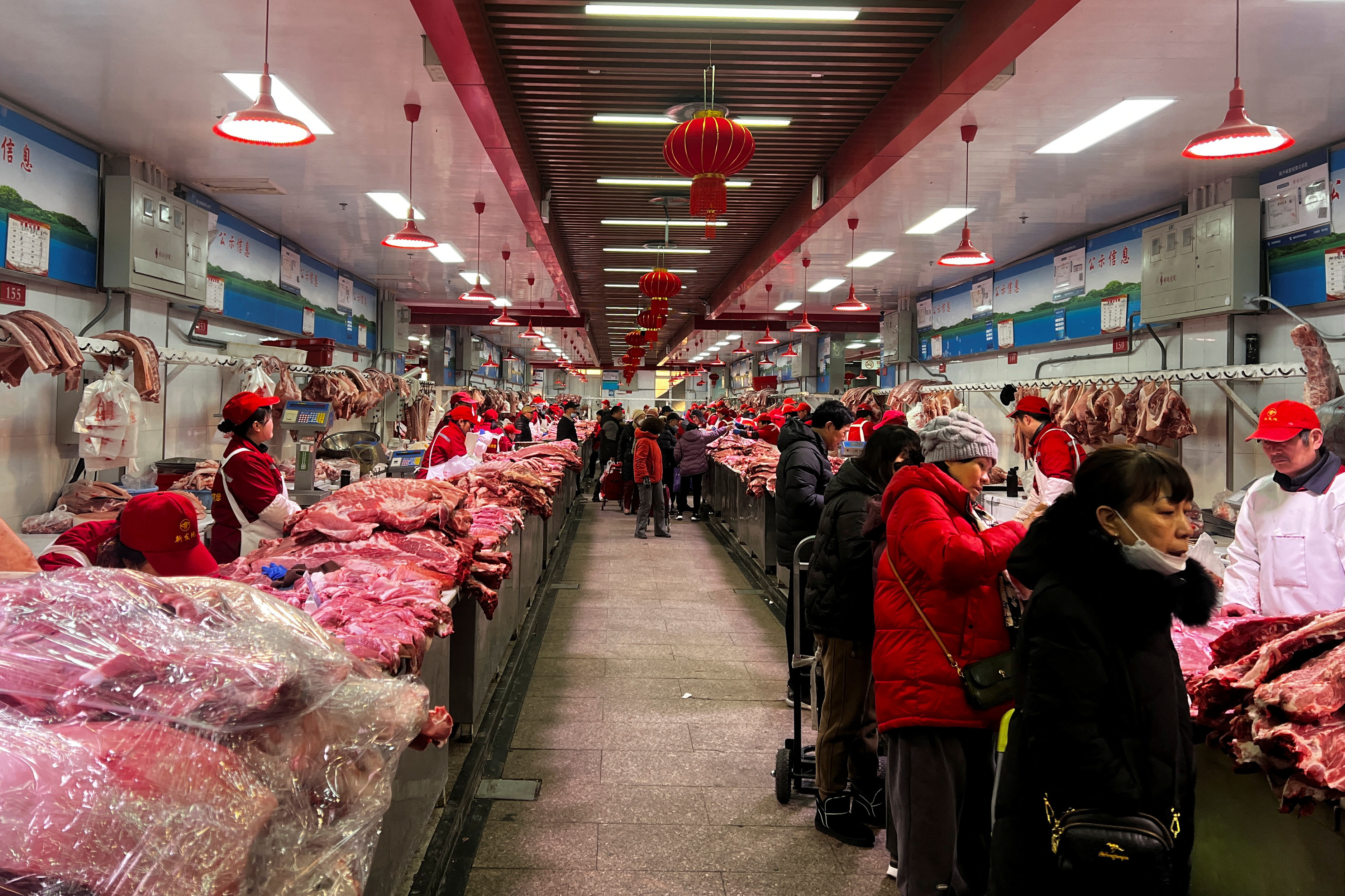 Pork sellers attend to customers at a market in Beijing