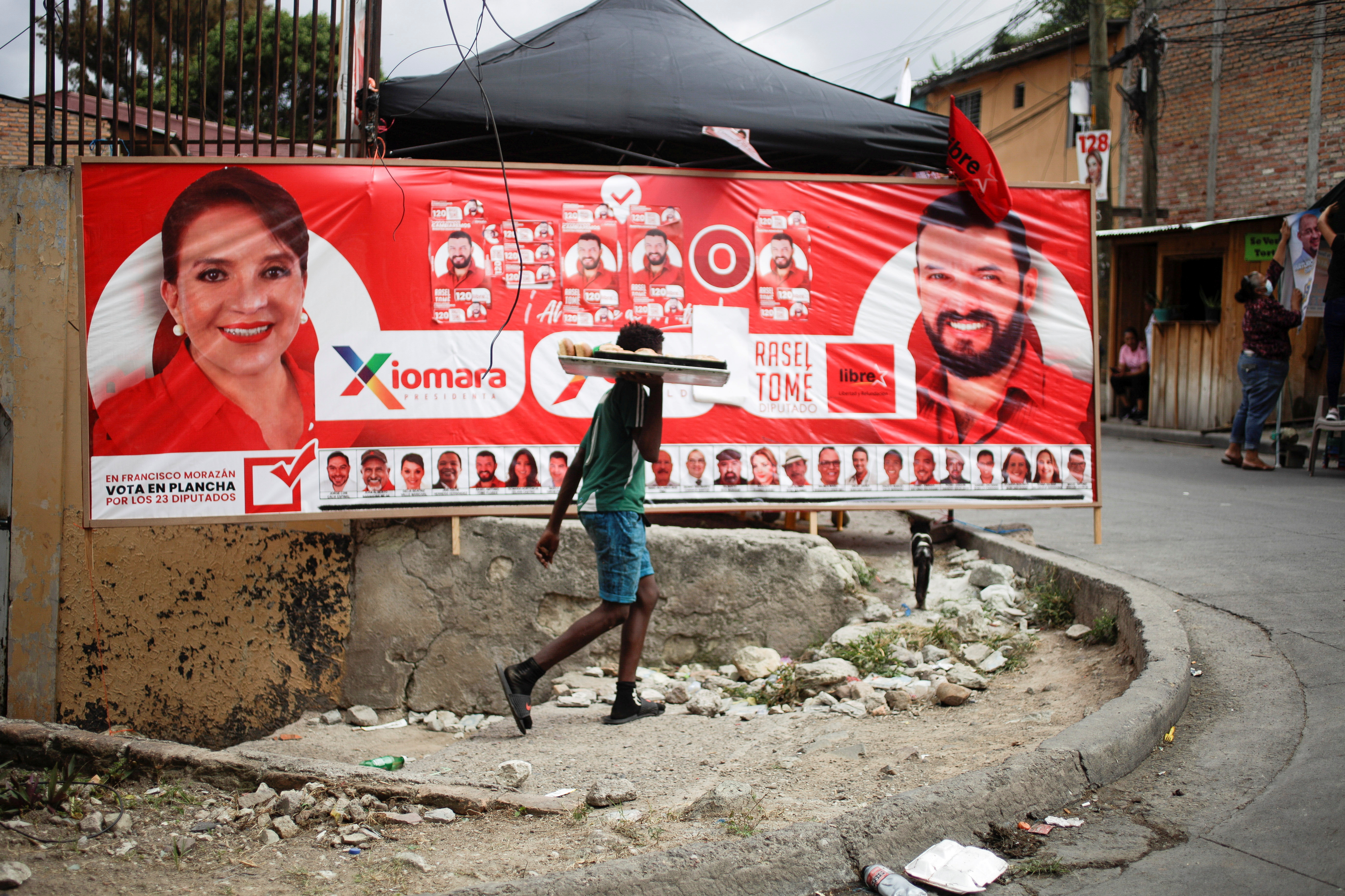 A young man passes in front of a banner of the Libre Party presidential candidate Xiomara Castro ahead of the November 28 general election in Tegucigalpa, Honduras November 27, 2021. REUTERS/Fredy Rodriguez/File Photo