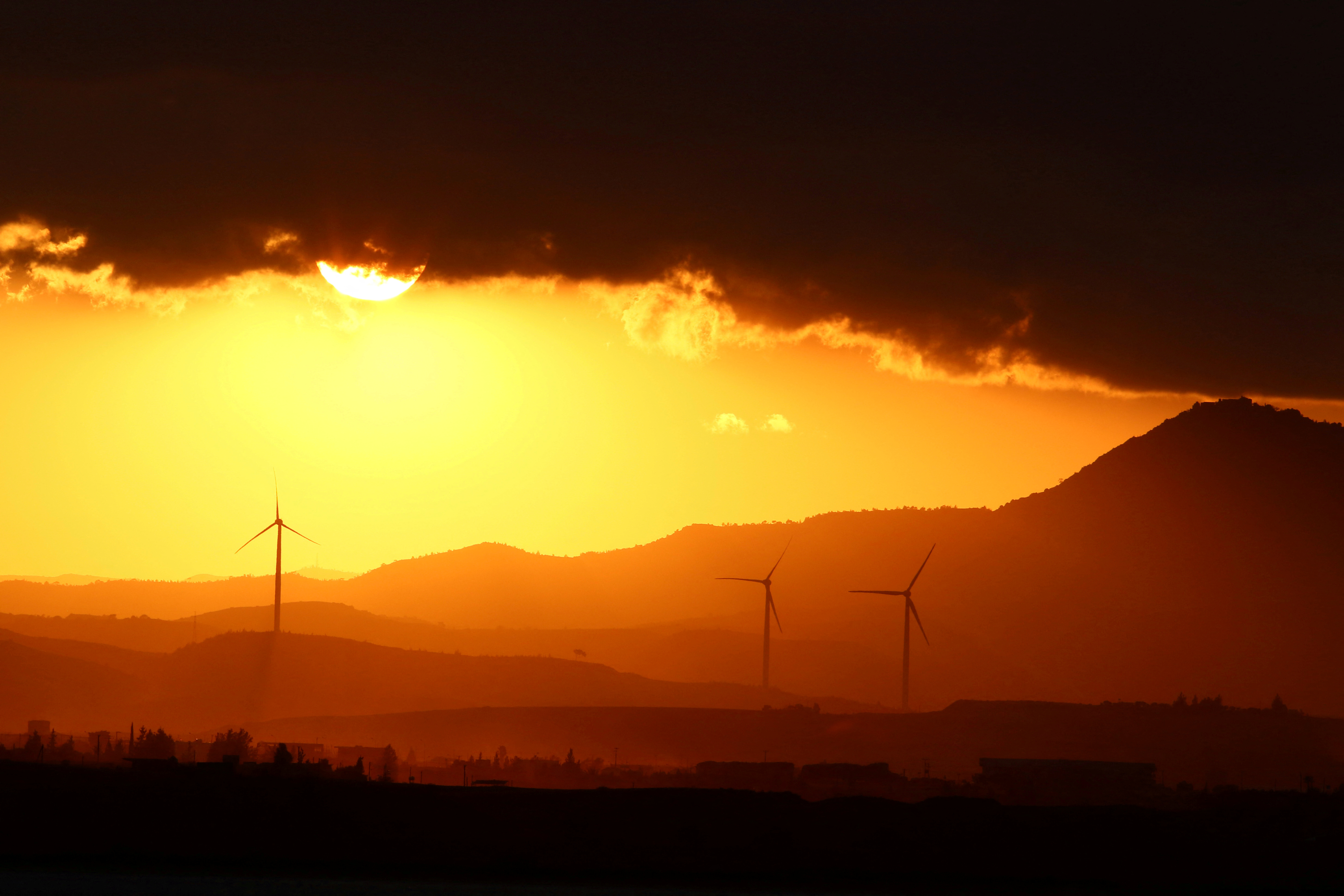 Power-generating windmill turbines are pictured during the sunset near Larnaca