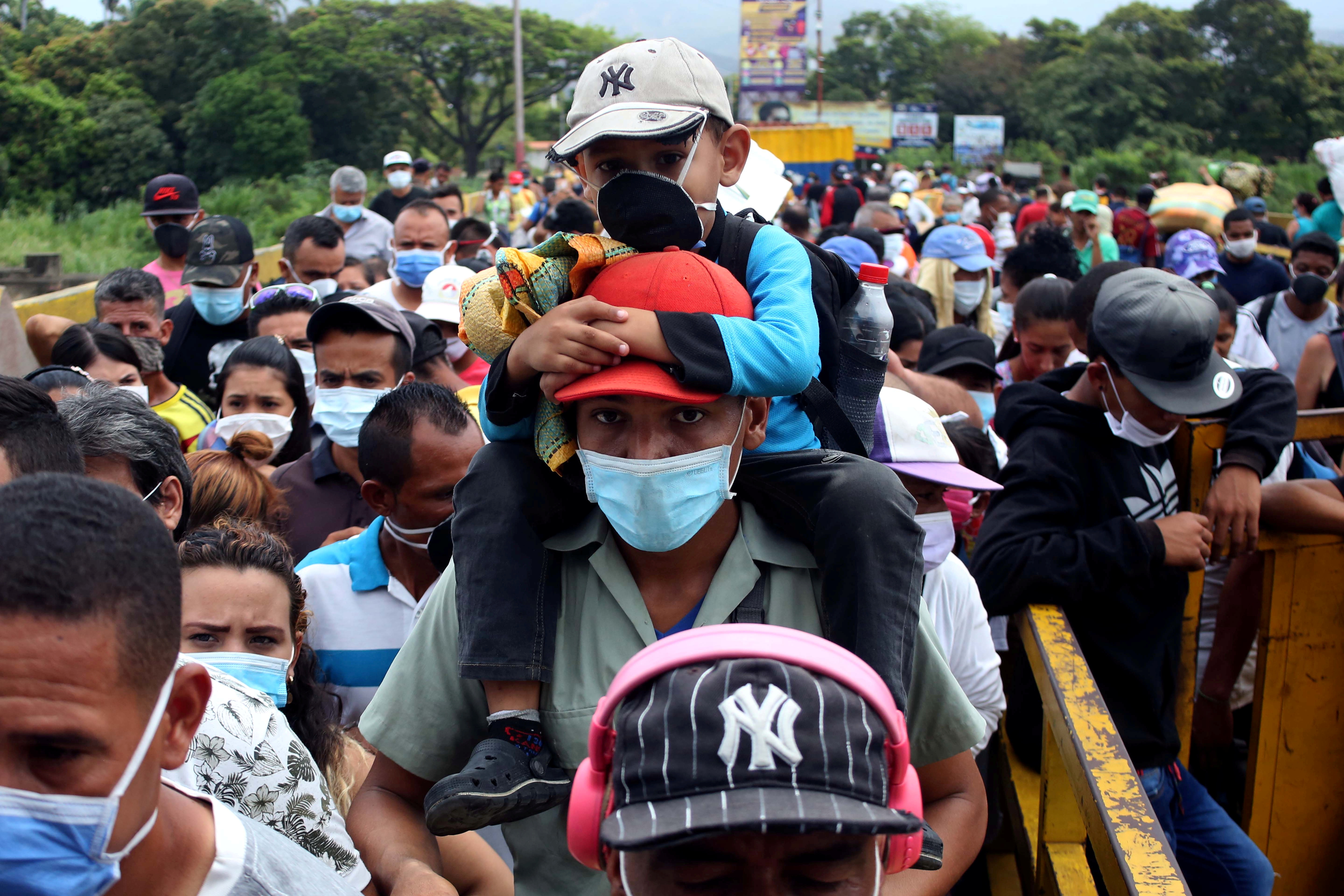 People wearing protective face masks line up to cross the border between Colombia and Venezuela at Simon Bolivar international bridge in Cucuta