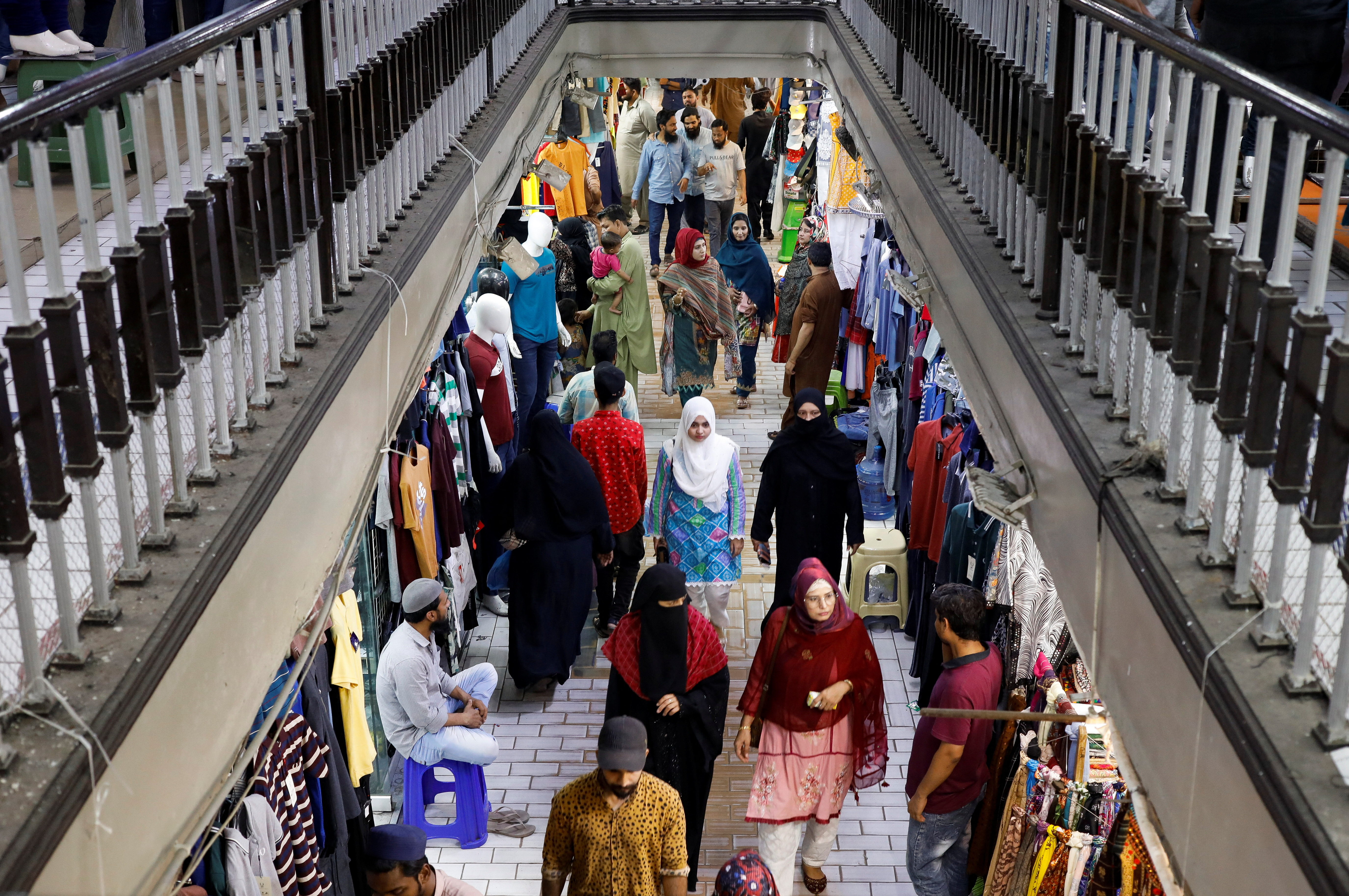 People walk as they shop in a market, ahead of Eid al-Fitr celebrations in Karachi