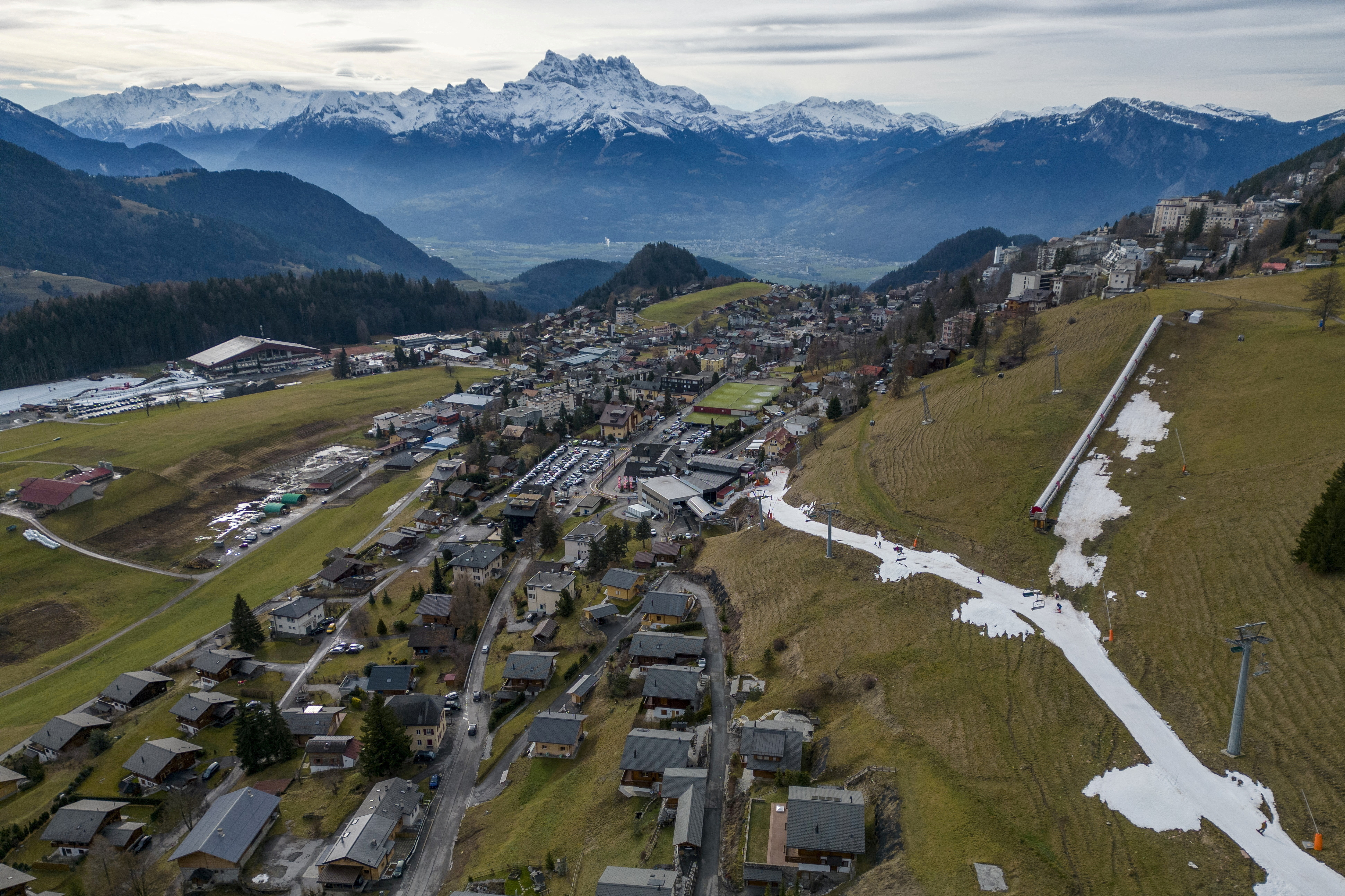 Skiers pass on a small layer of artificial snow in Leysin