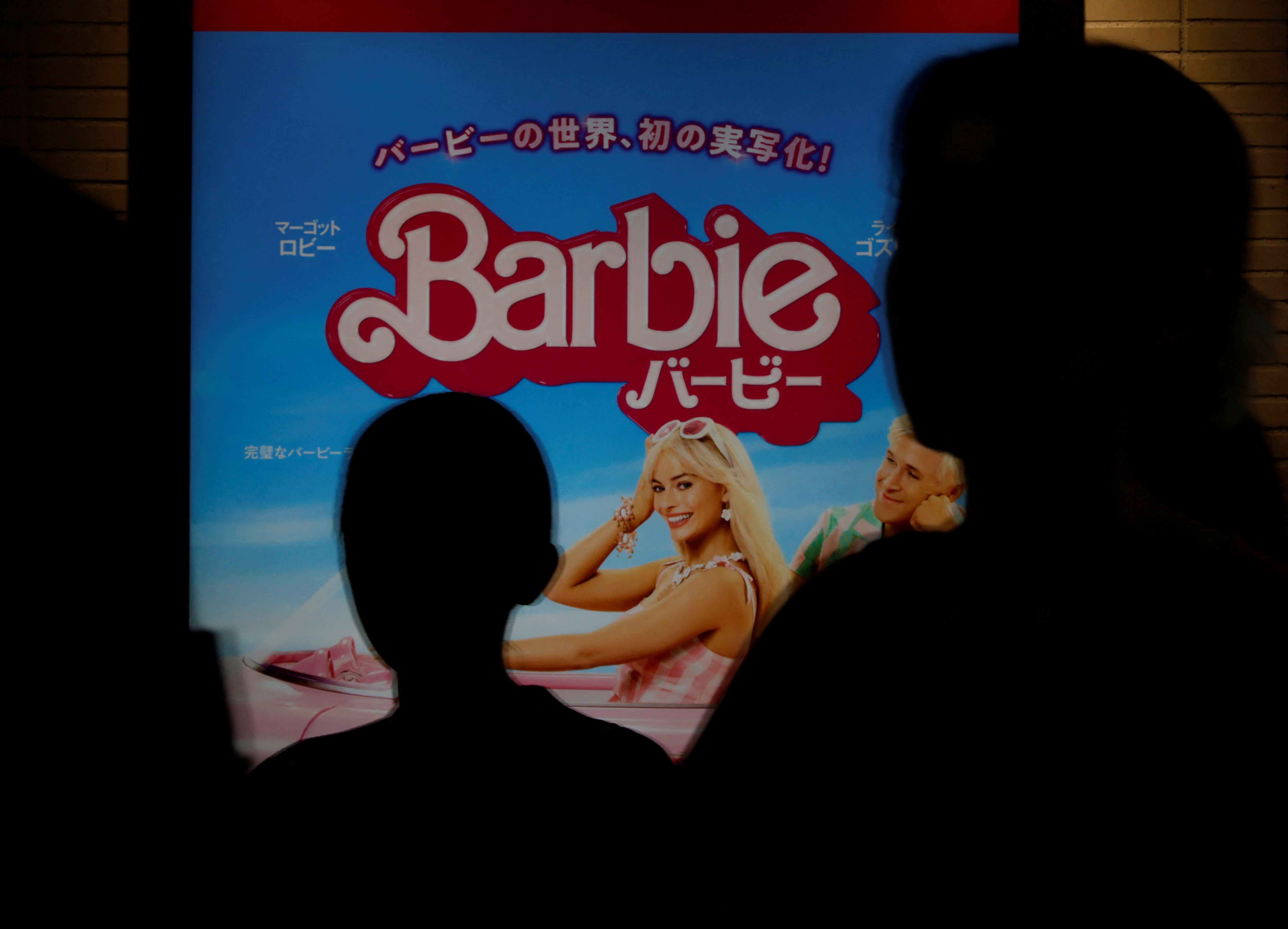 People walk past a promotional poster of film 