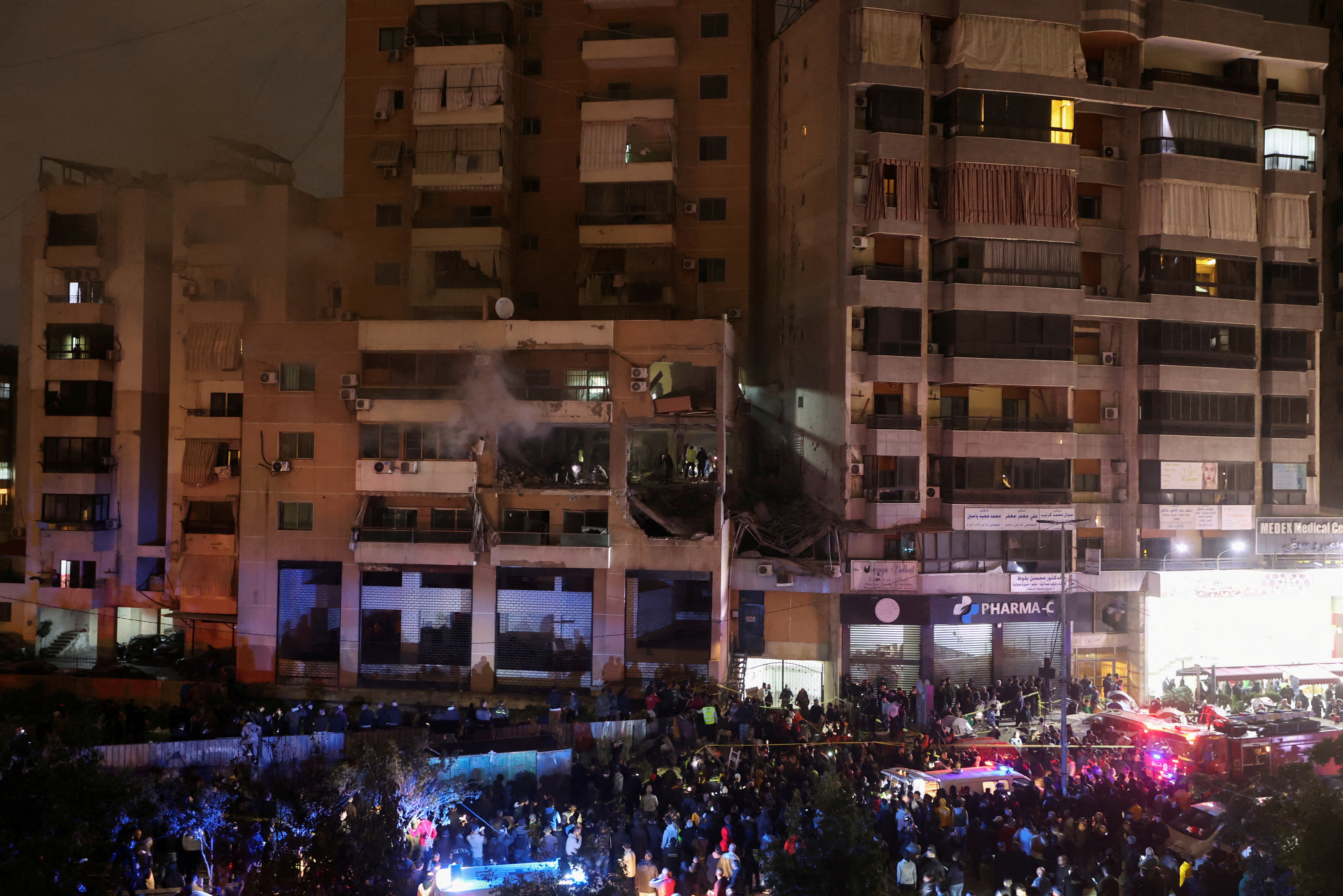 People gather near a damaged site following an explosion at Beirut suburb of Dahiyeh
