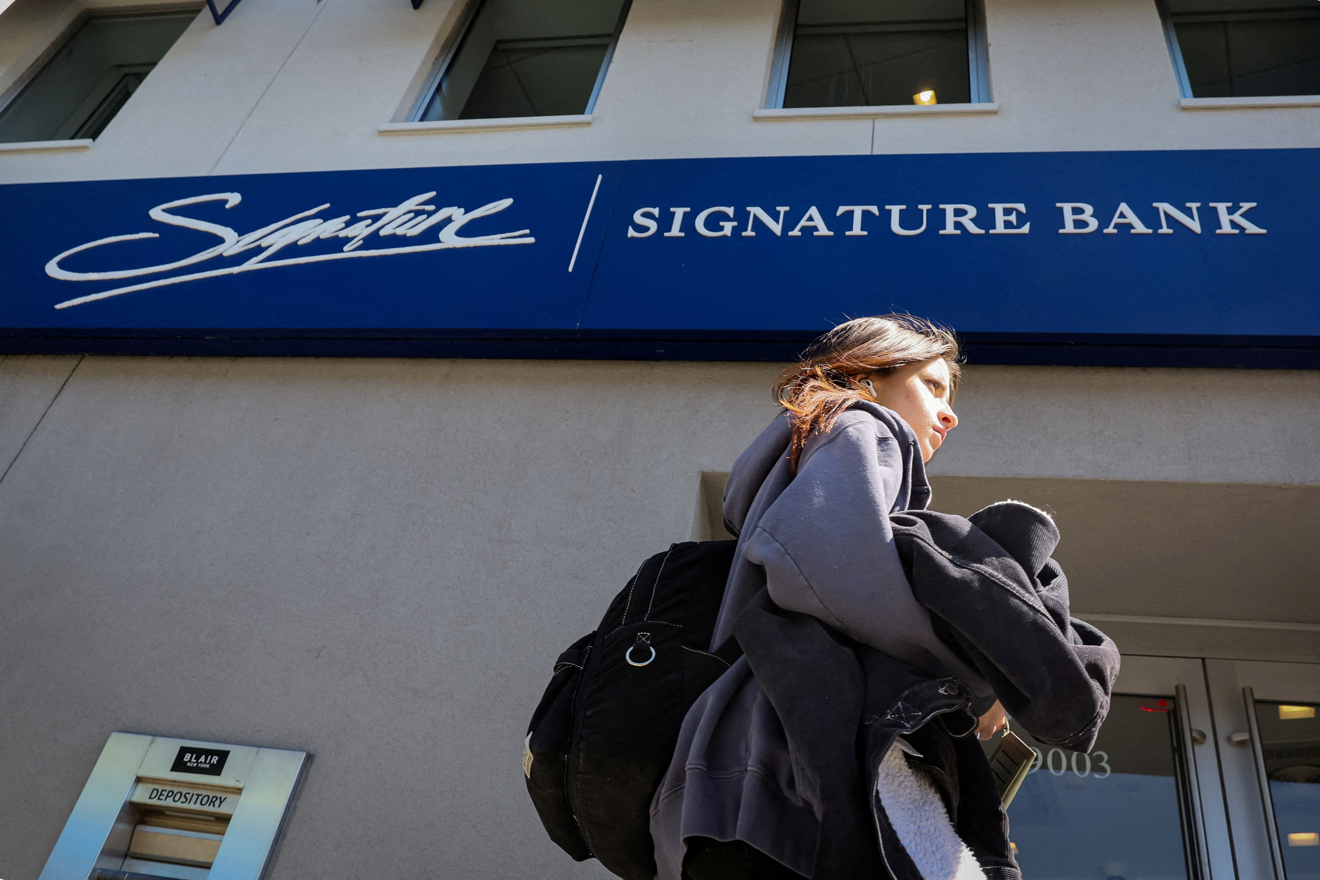 A woman walks past a Signature Bank location in Brooklyn, New York