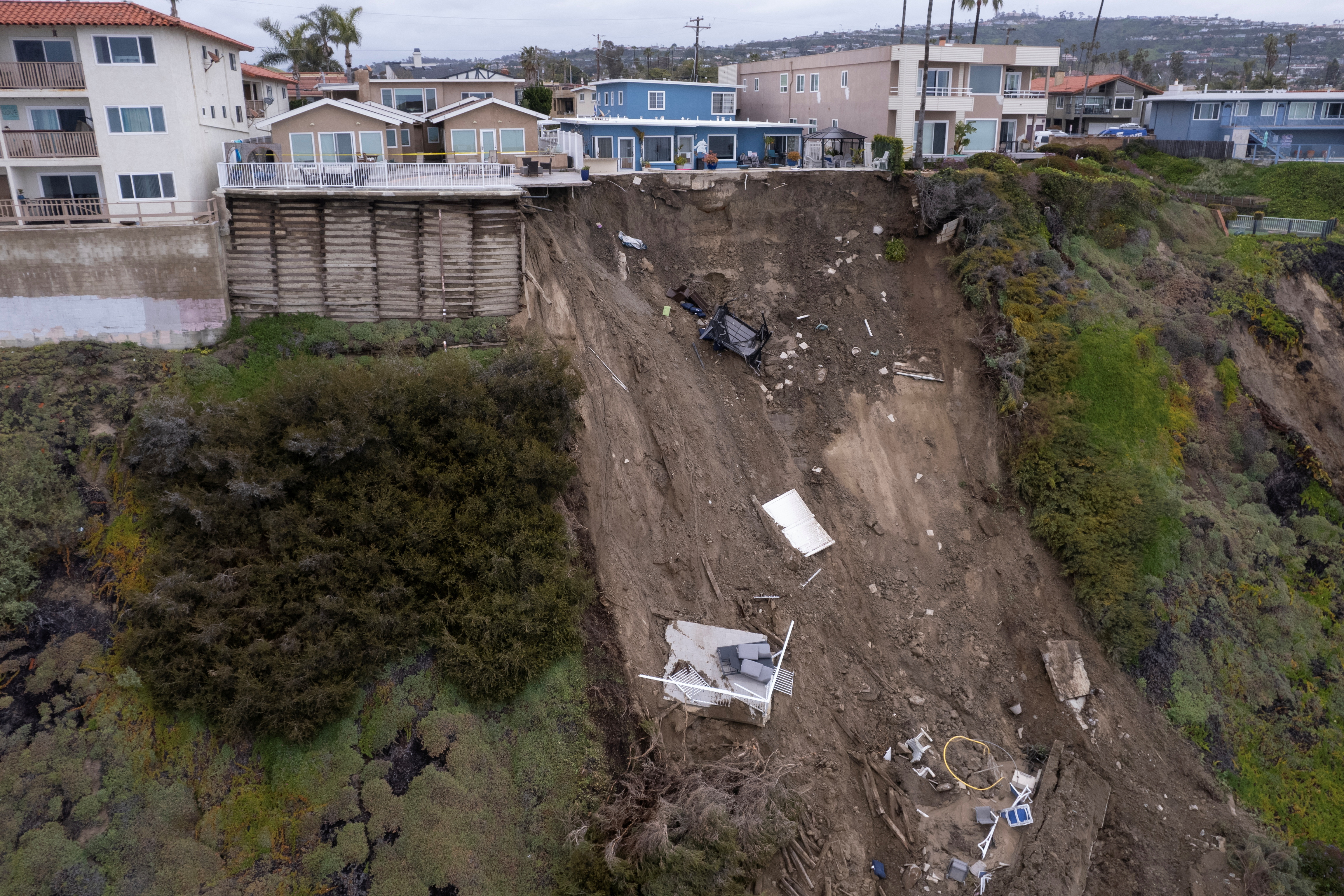 A backyard pool hangs on cliffside after torrential rains hits California beachtown