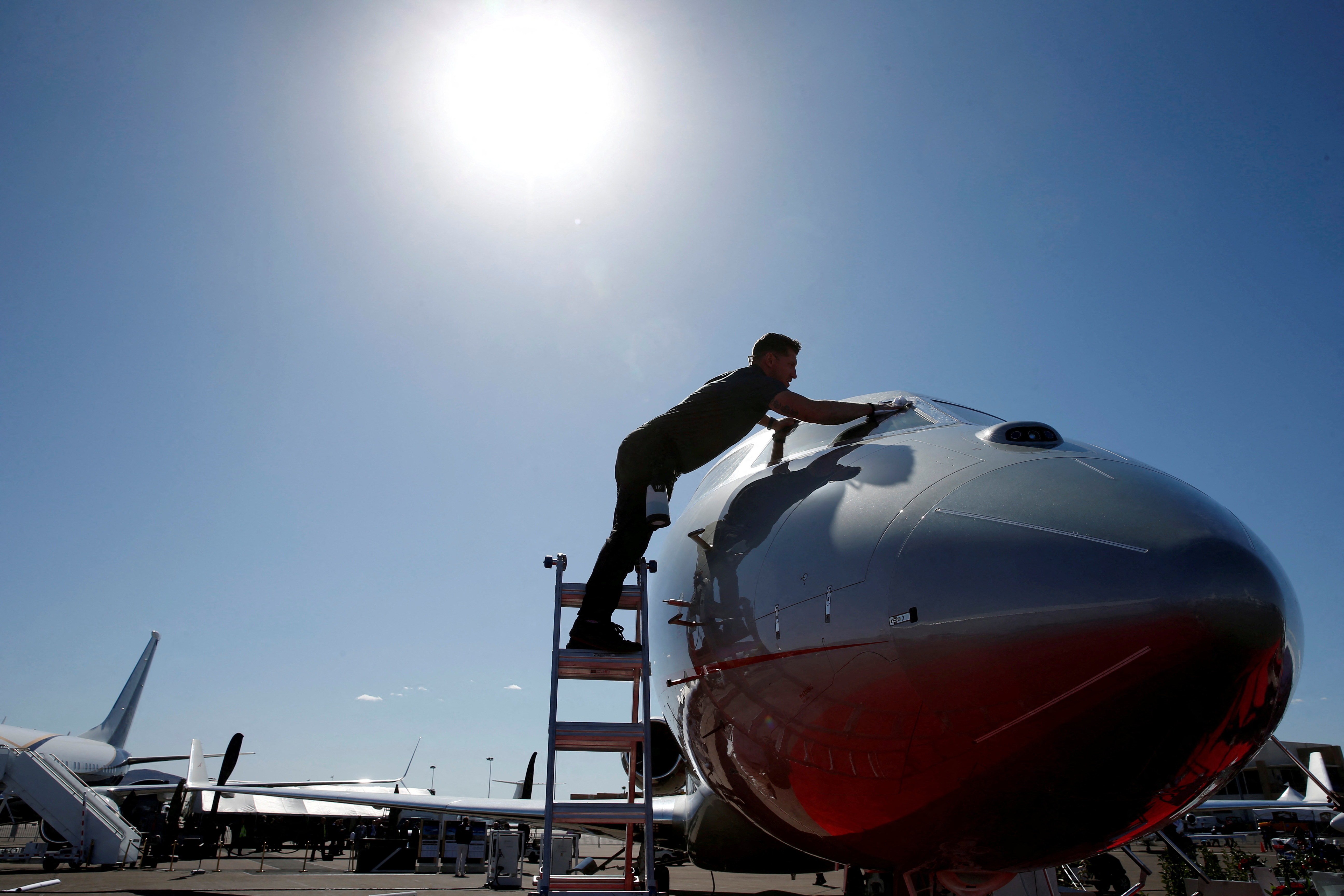 An aircraft detailer cleans the windshield of a business jet