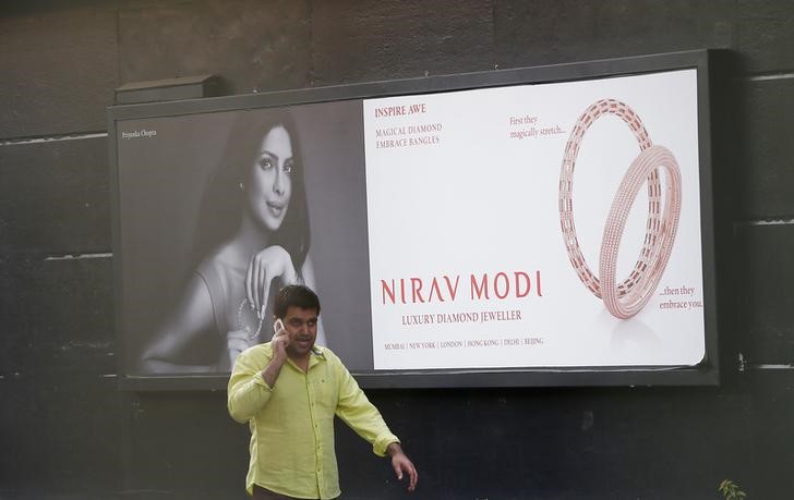 Man talks on a phone as he walks past a Nirav Modi showroom in New Delhi