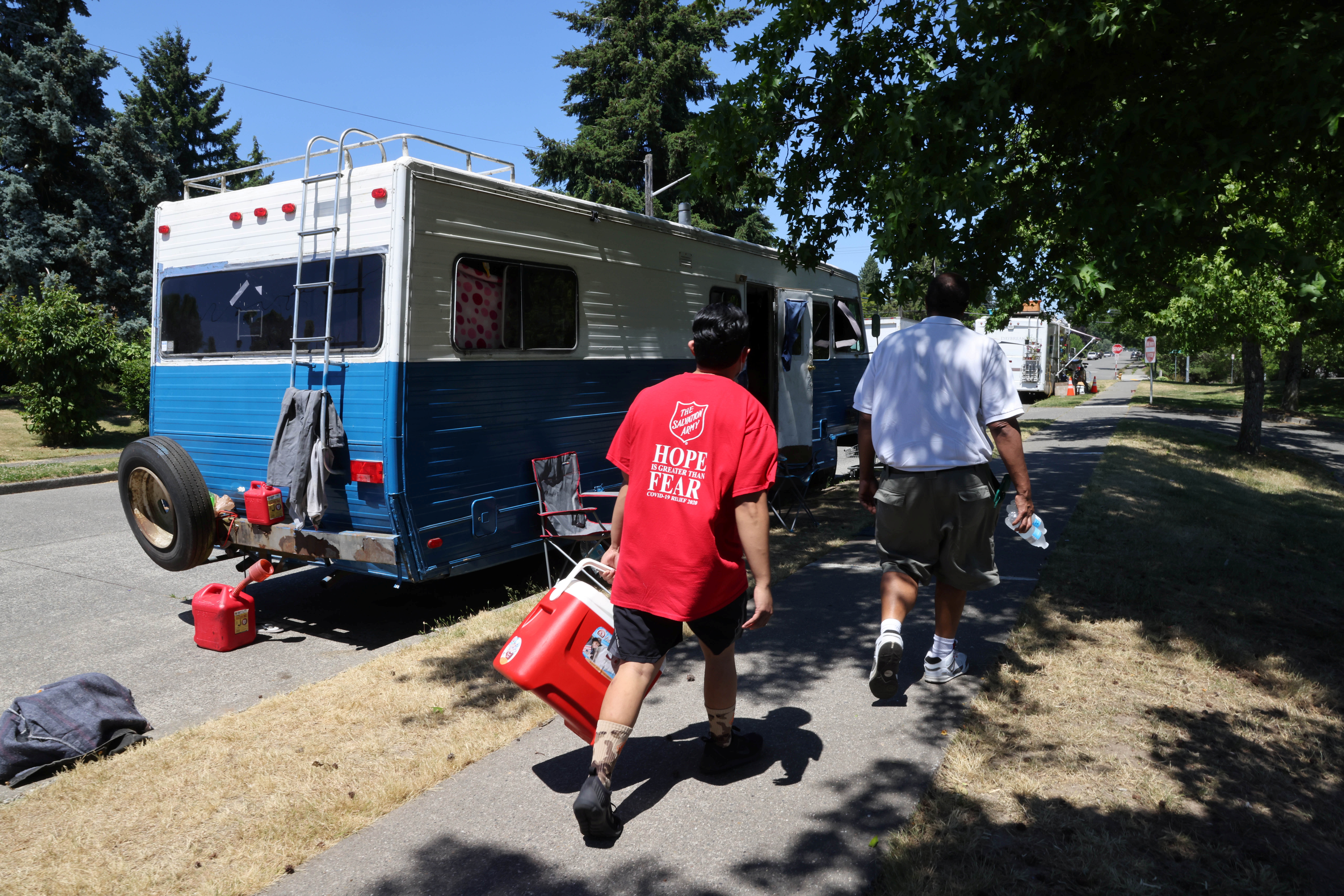 Shanton Alcaraz and Steve Huntley from the Salvation Army Northwest Division hand out water to people who might need it and invite them to their nearby cooling center for food and beverages during a heat wave in Seattle, Washington, U.S., June 27, 2021. REUTERS/Karen Ducey