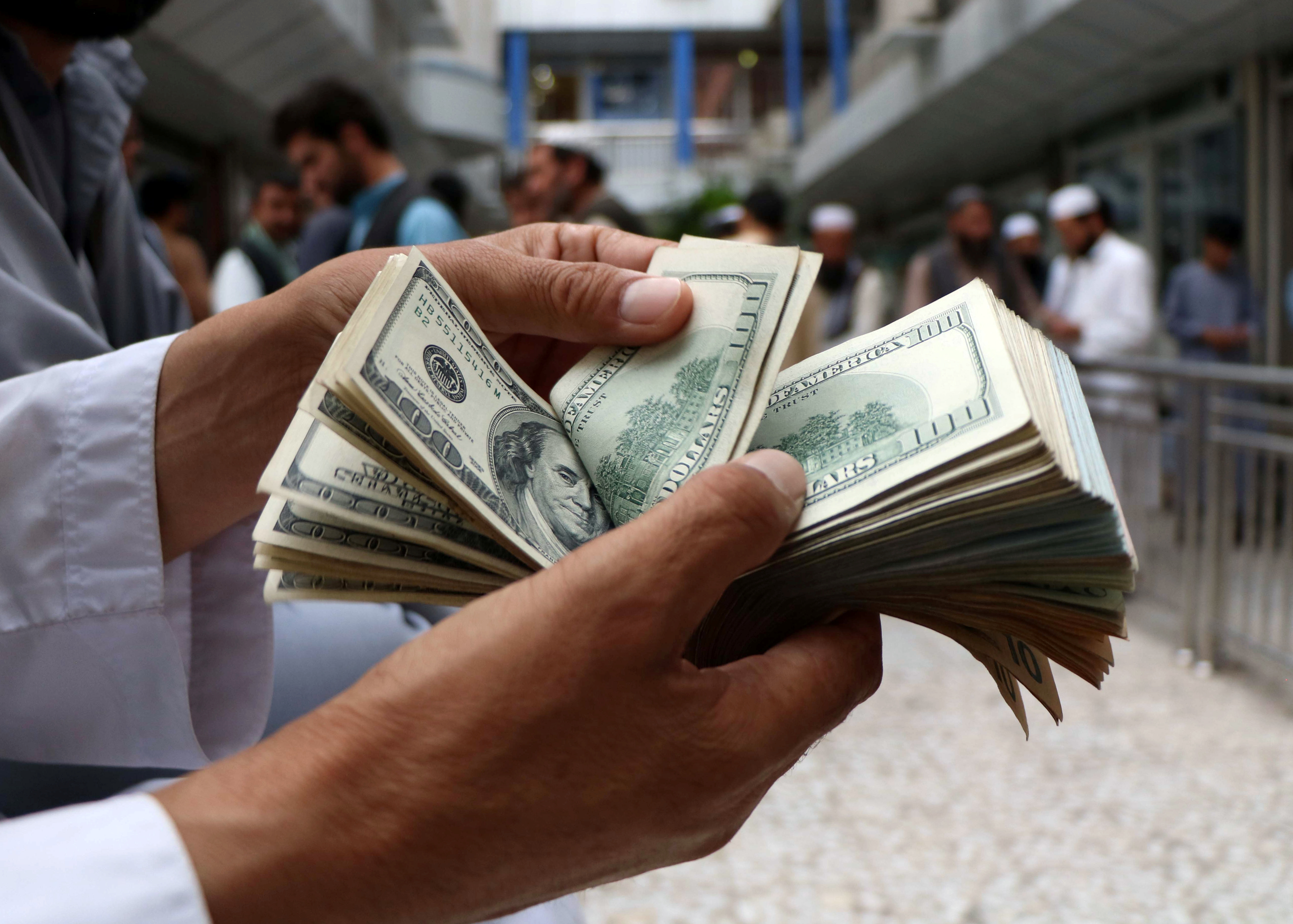 A money changer counts U.S. dollar banknotes at money change market in Herat province