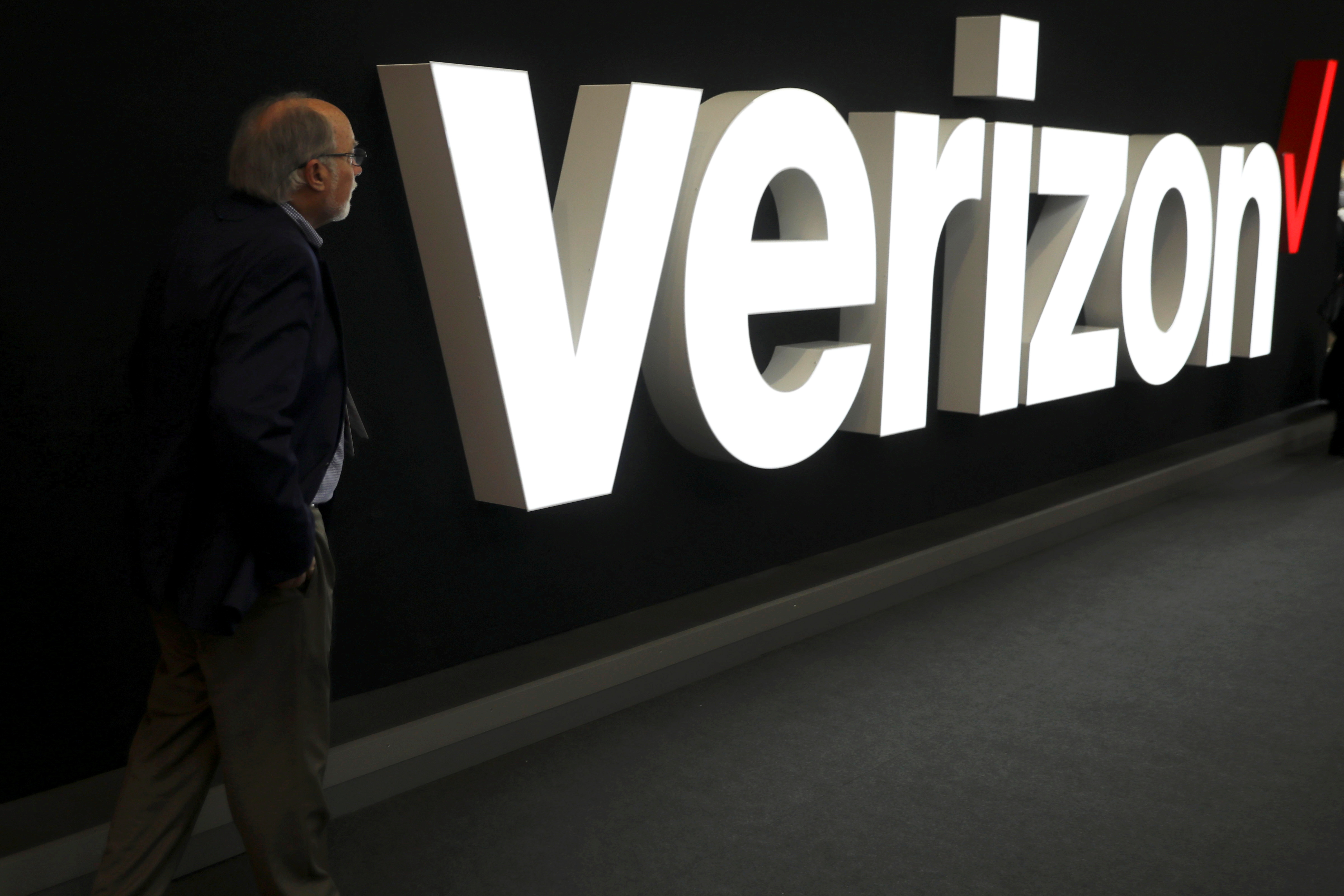 A man stands next to the logo of Verizon at the Mobile World Congress in Barcelona