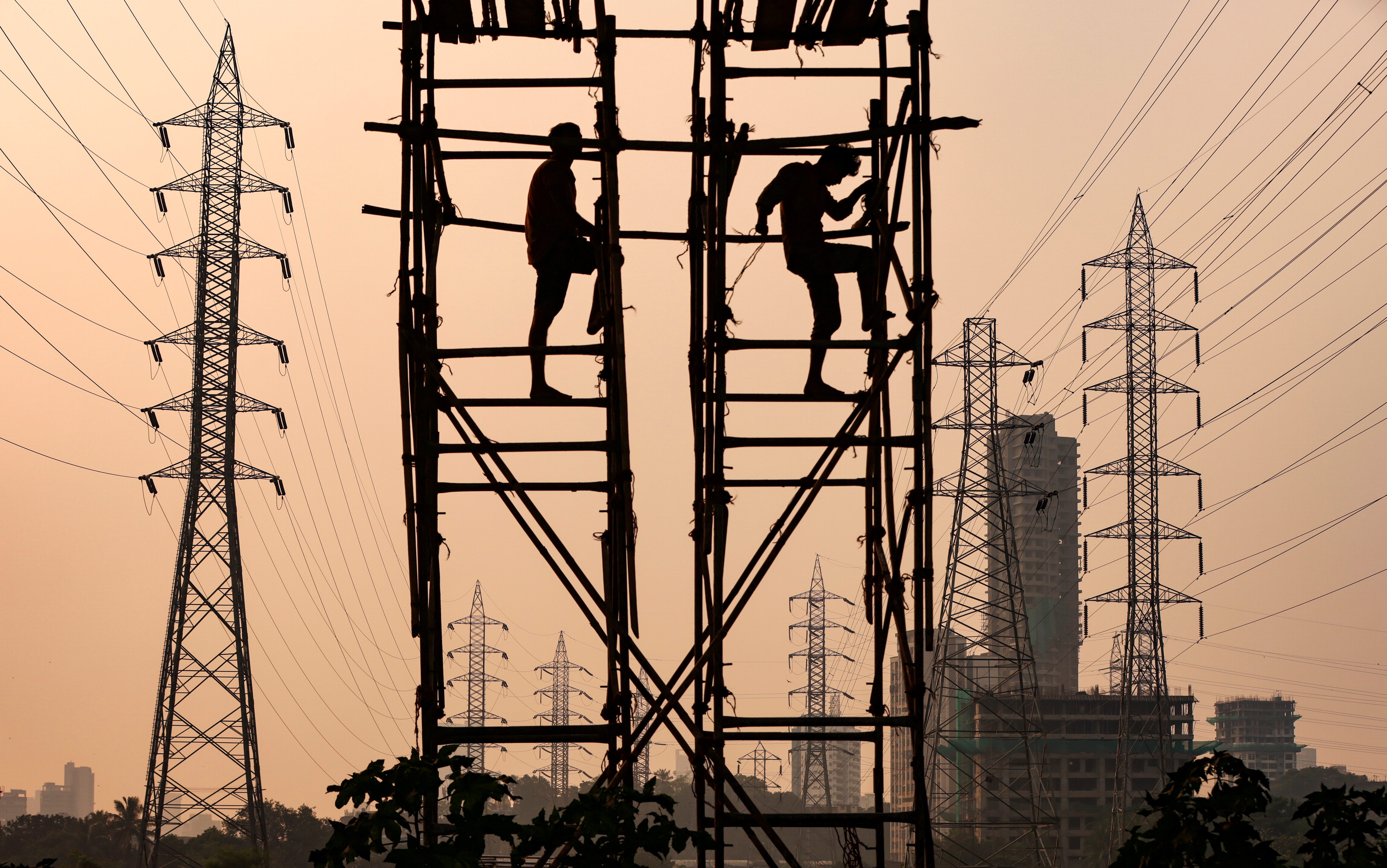 Labourers work next to electricity pylons in Mumbai
