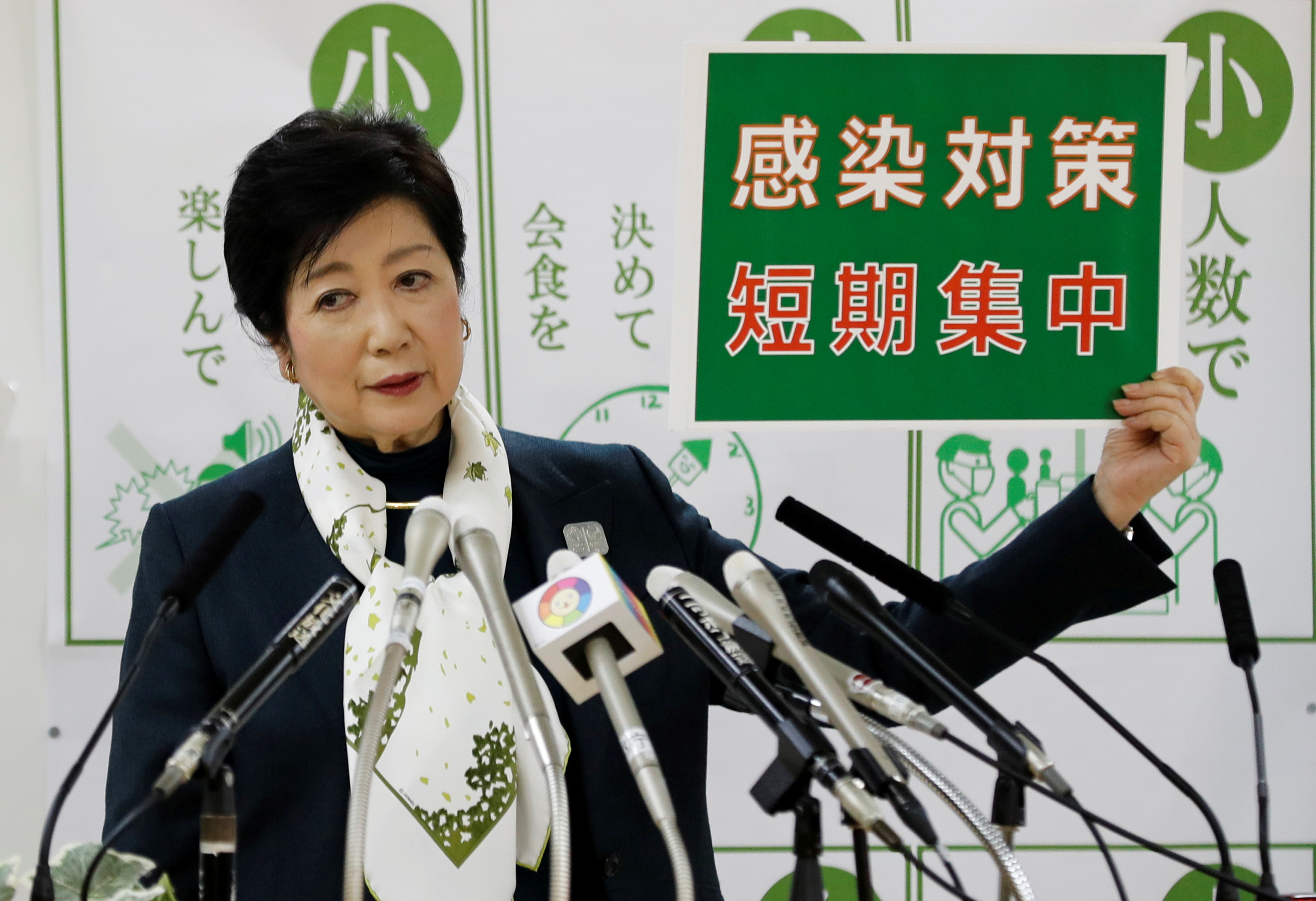 Tokyo Governor Yuriko Koike holds a sign that reads: 