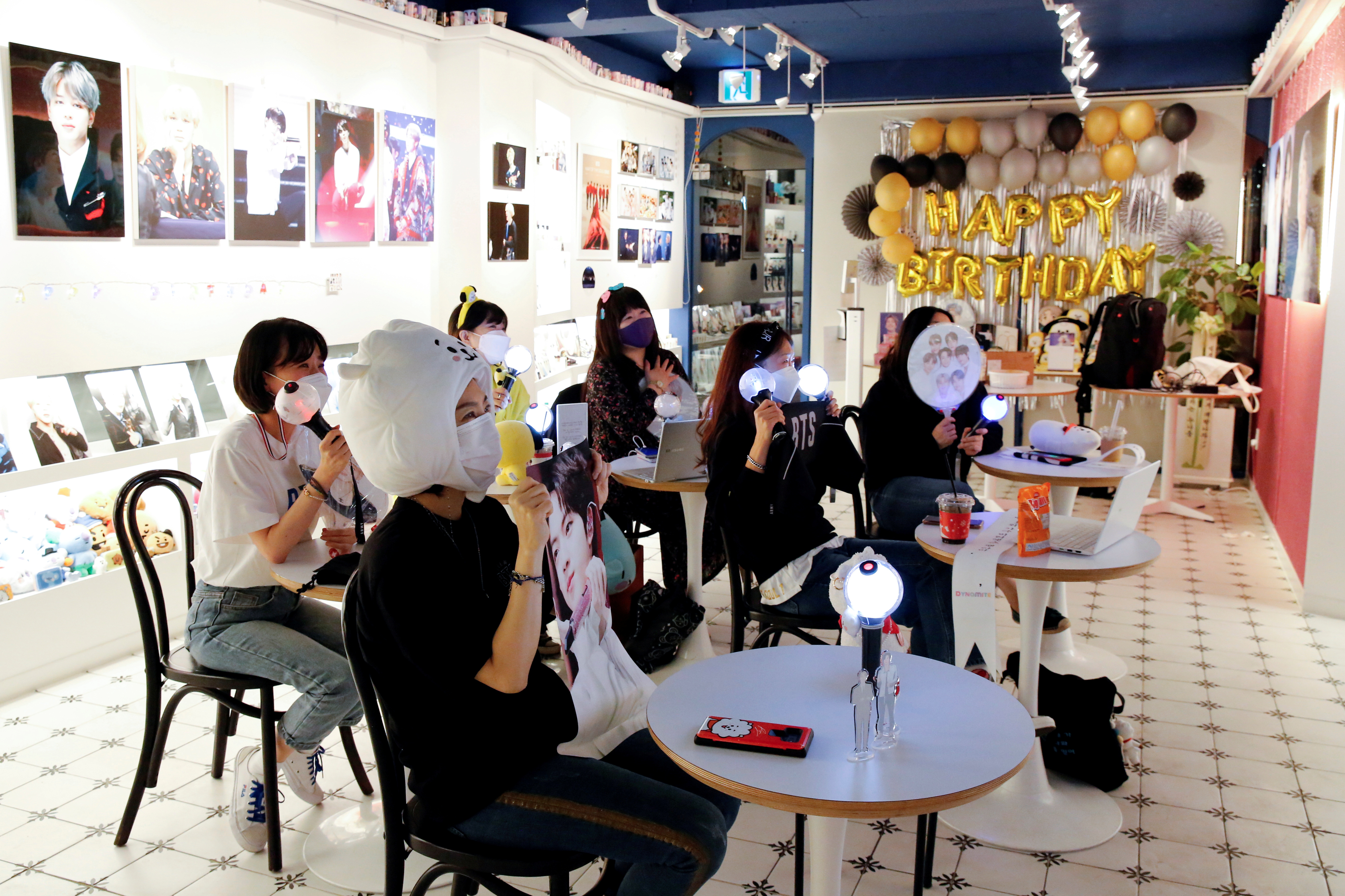 Fans of K-pop idol boy band BTS enjoy as they watch a live streaming online concert, wearing a protective masks at a cafe, in Seoul