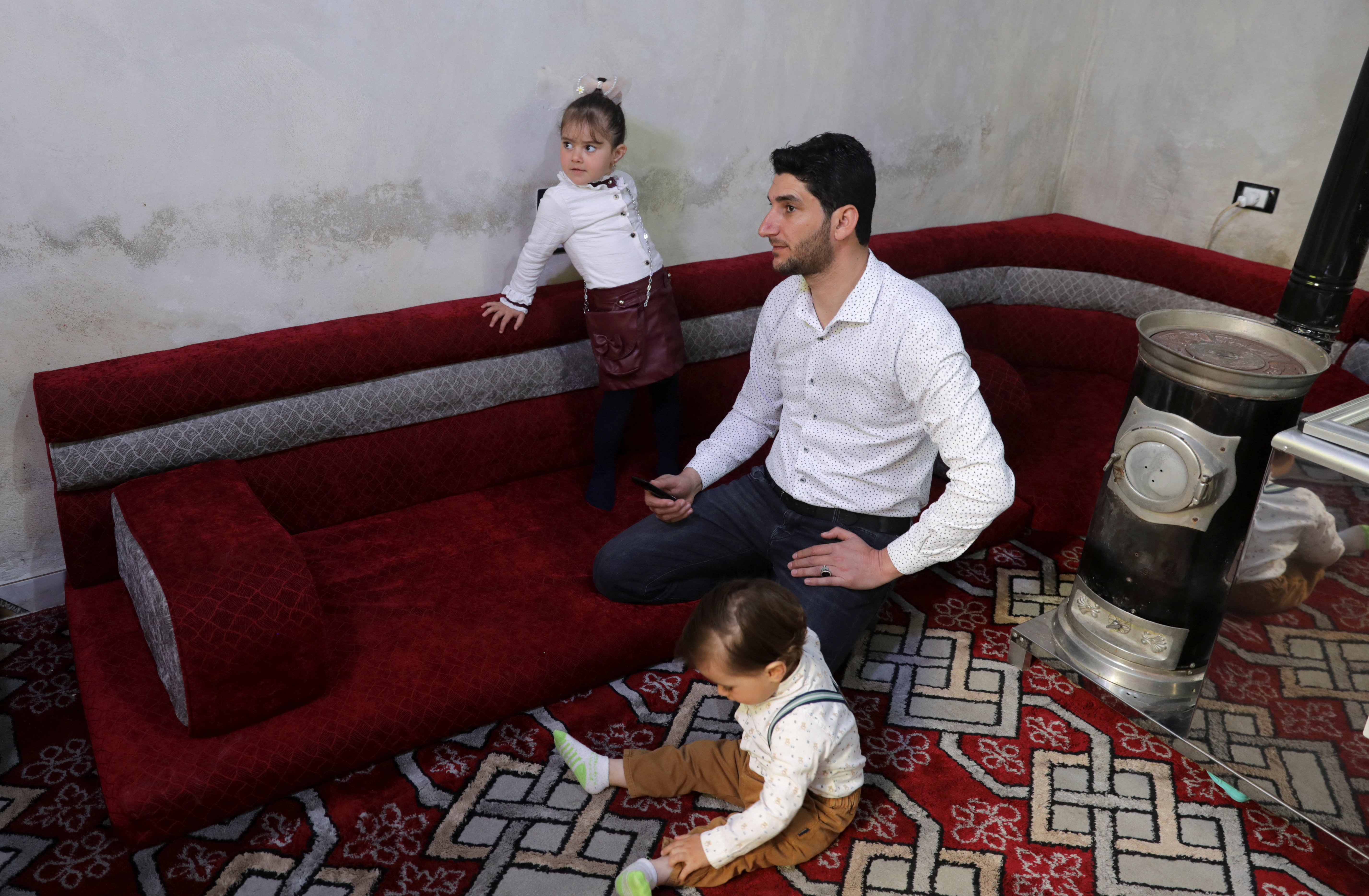Abdel Hamid al-Youssef sits with his children at his home in the rebel-held town of Sarmada