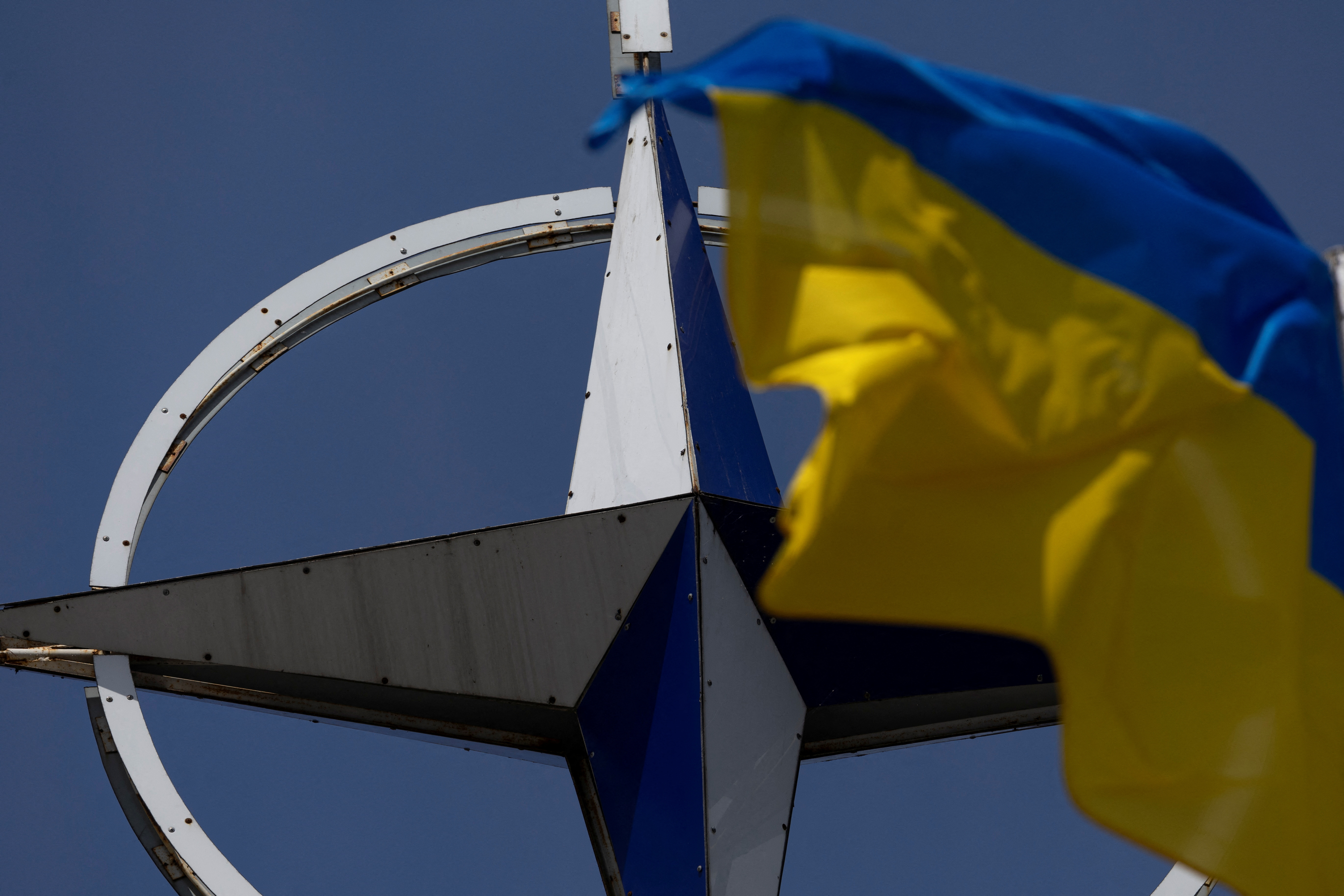 Ukrainian national flag rises in front of the NATO emblem in central Kyiv