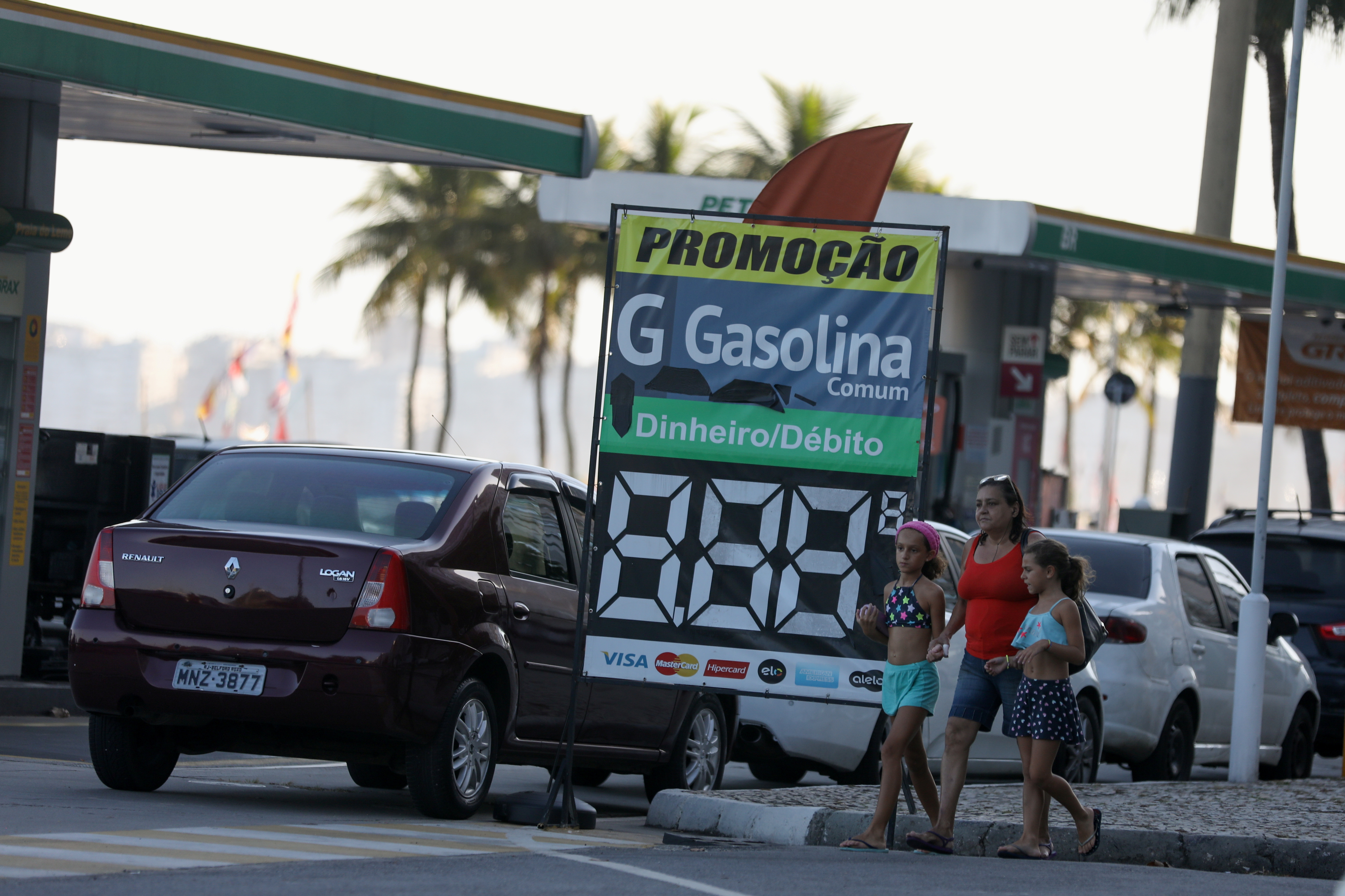 People walk as cars line up at a gas station, in Rio de Janeiro