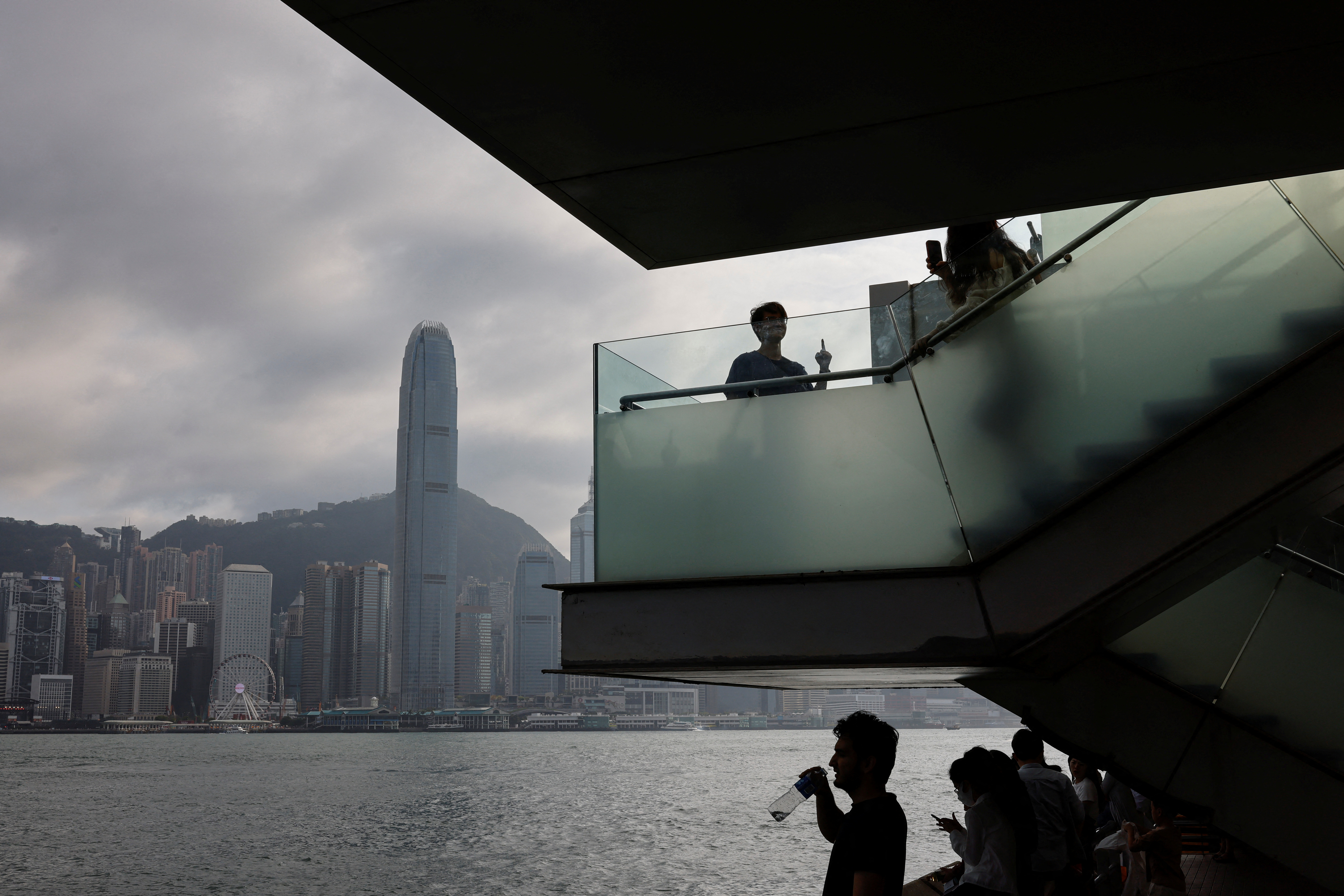 Mainland Chinese tourists look out at the skyline of buildings at Tsim Sha Tsui, in Hong Kong