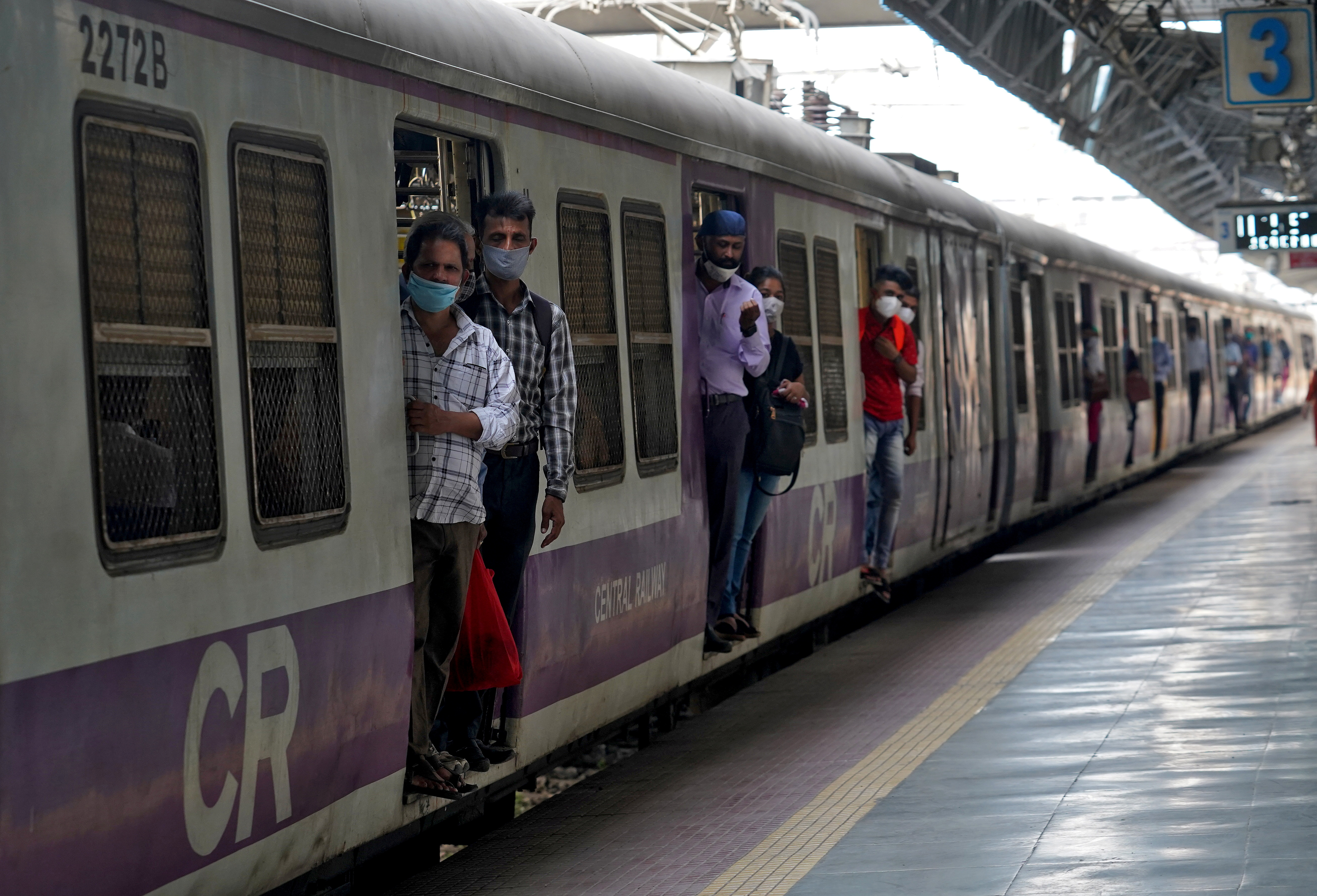 Commuters wearing protective face masks travel in a suburban train in Mumbai