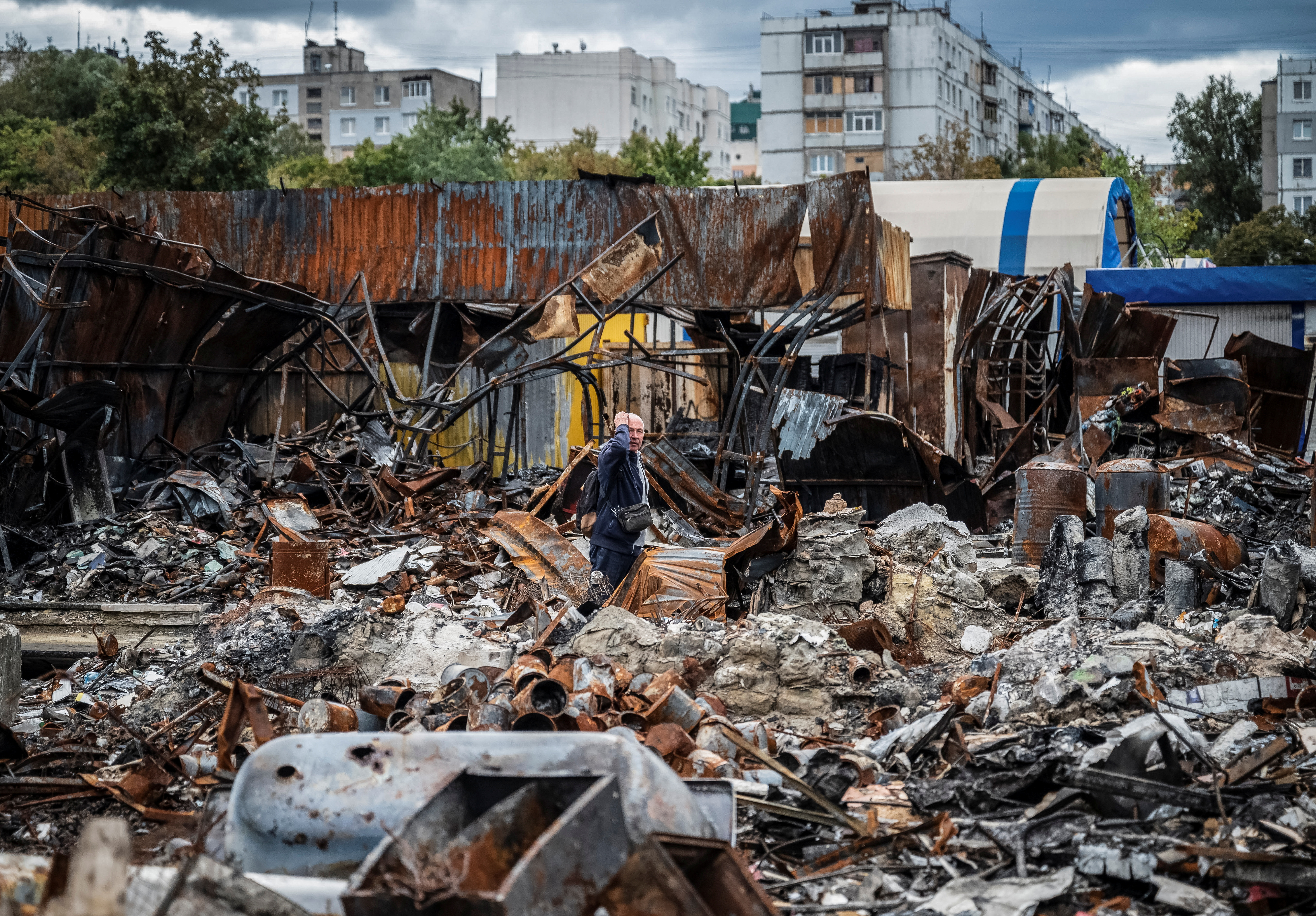 A local resident walks by a street market destroyed by military strikes, in Saltivka, one of the most damaged residential areas of Kharkiv