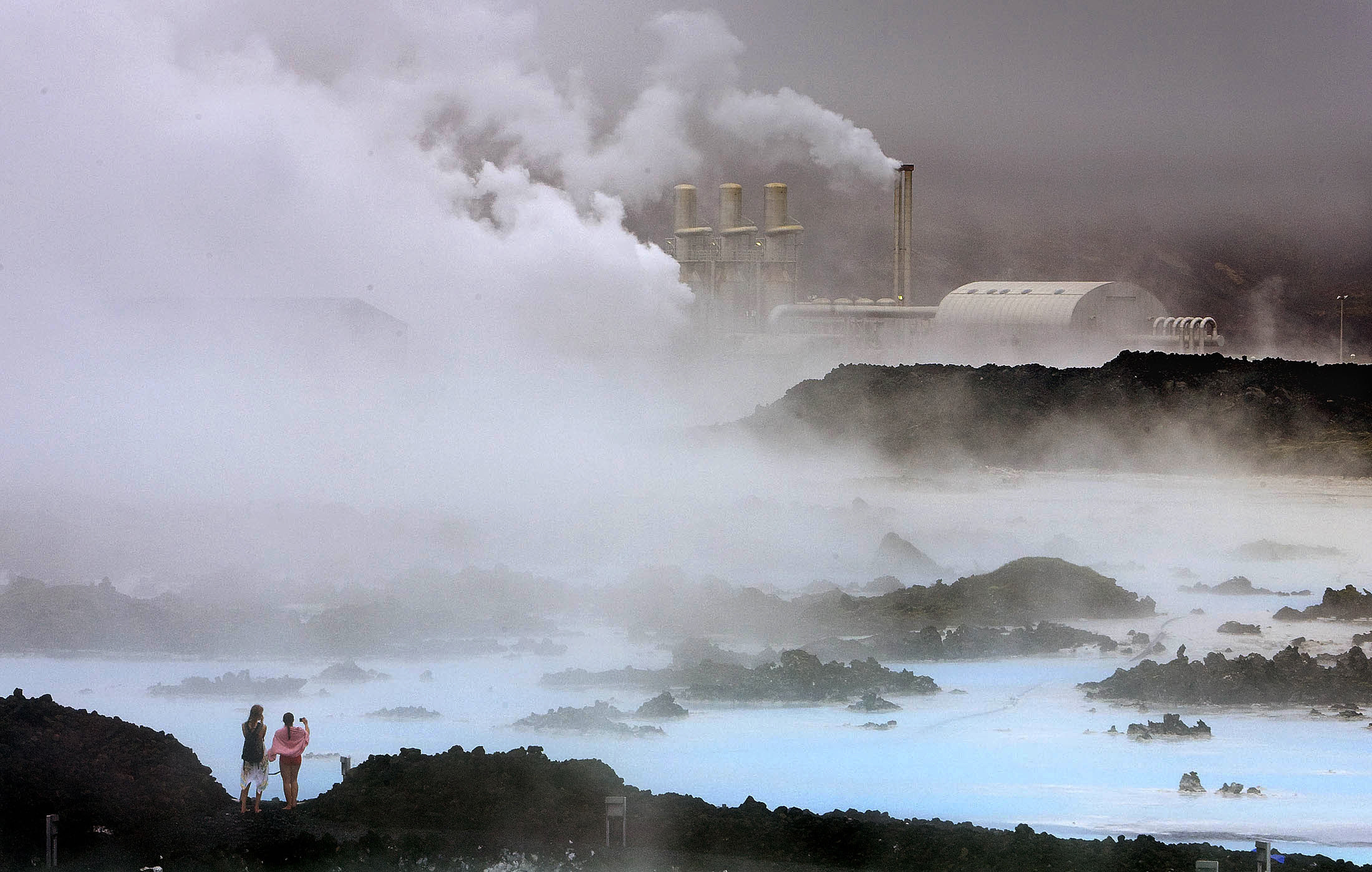 Visitors take pictures of the Svartsengi geothermal power plant near the Blue Lagoon hot springs outside the town of Grindavik