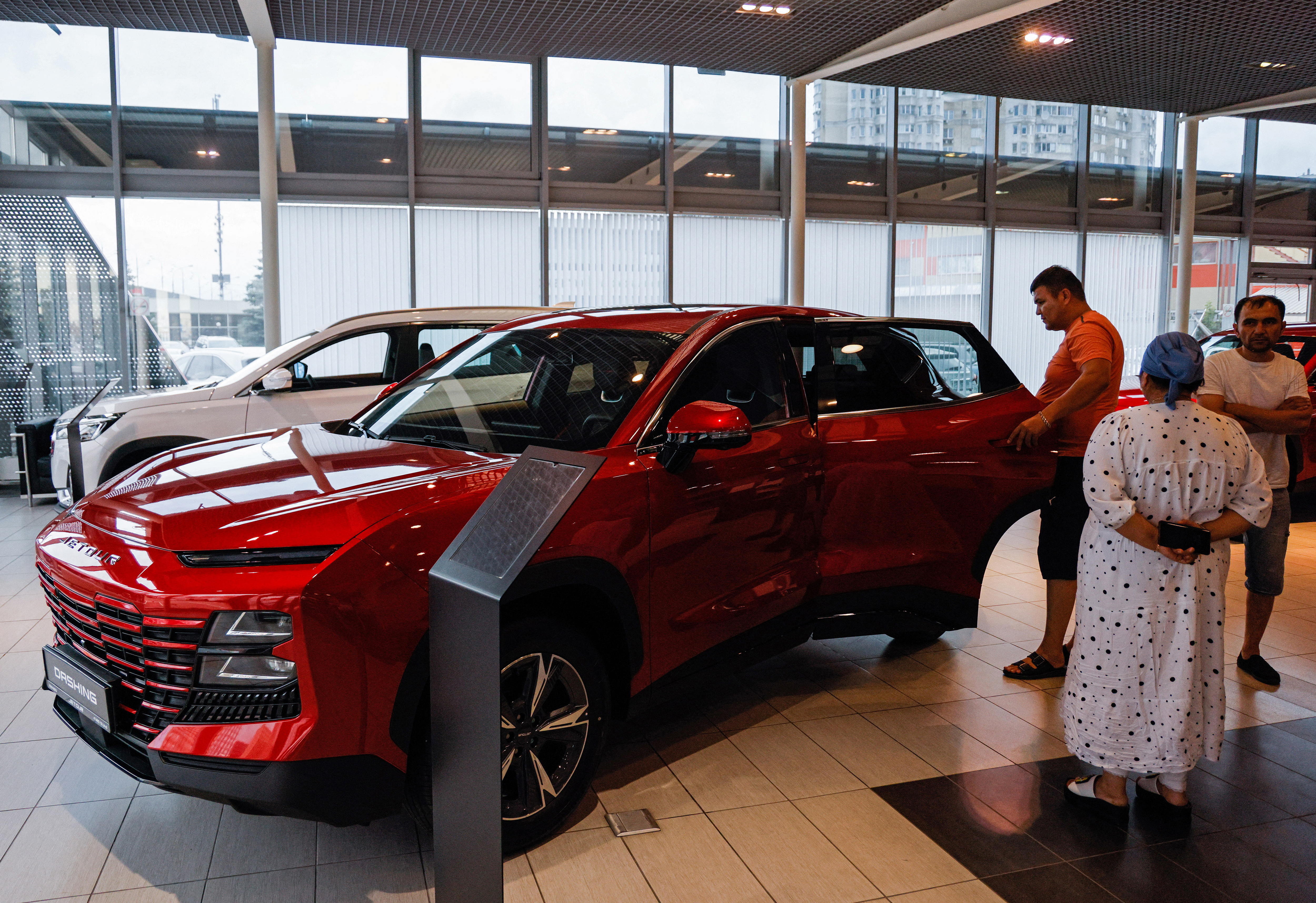 People inspect a Jetour Dashing crossover at a dealership in Lyubertsy