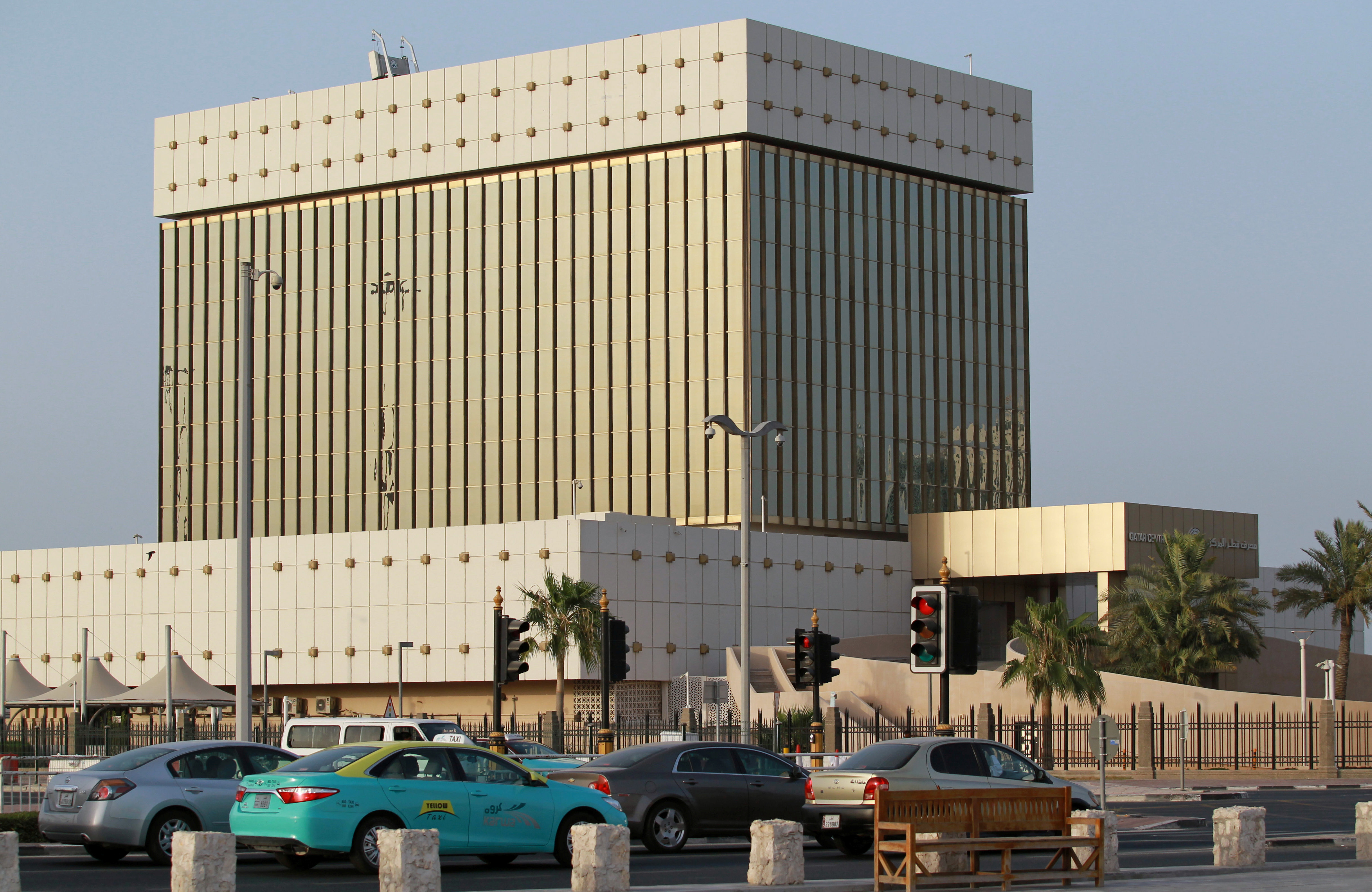 Cars drive past the building of Qatar Central Bank in Doha