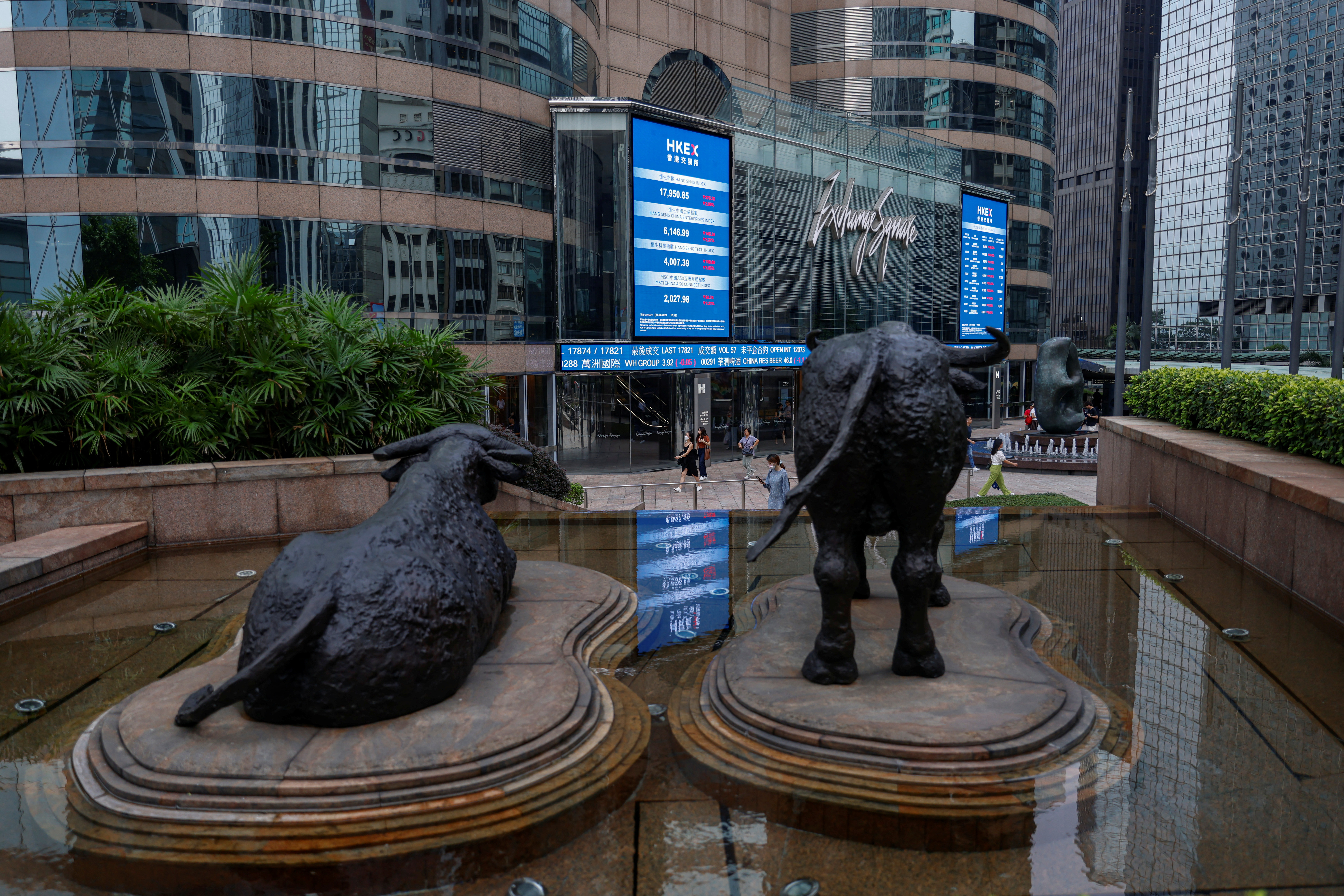 Bull statues are placed on screens showing the Hang Seng stock index and stock prices outside the Hong Kong Stock Exchange Square