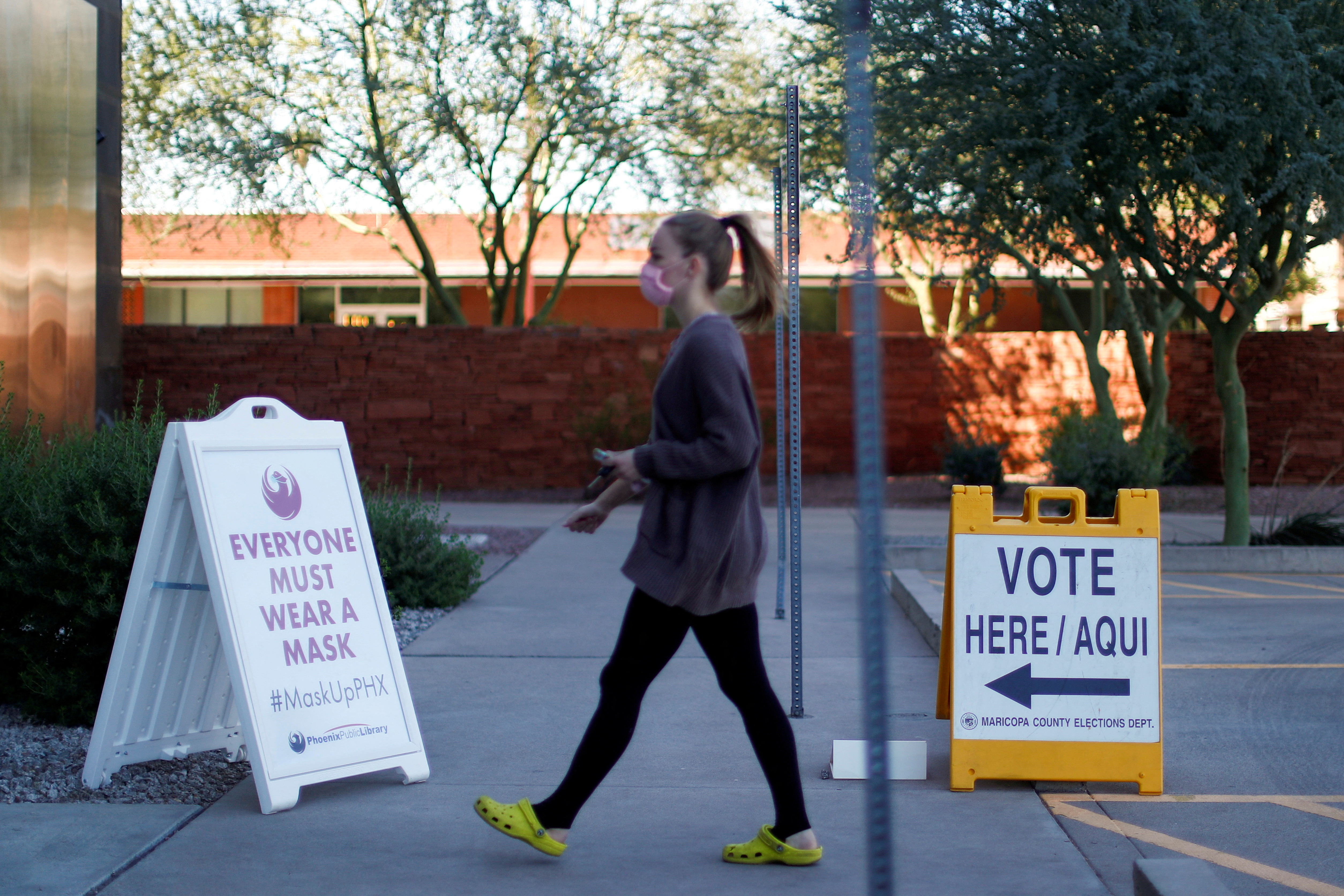 A woman walks to cast her ballot at the register of voters during early voting in Phoenix, Arizona