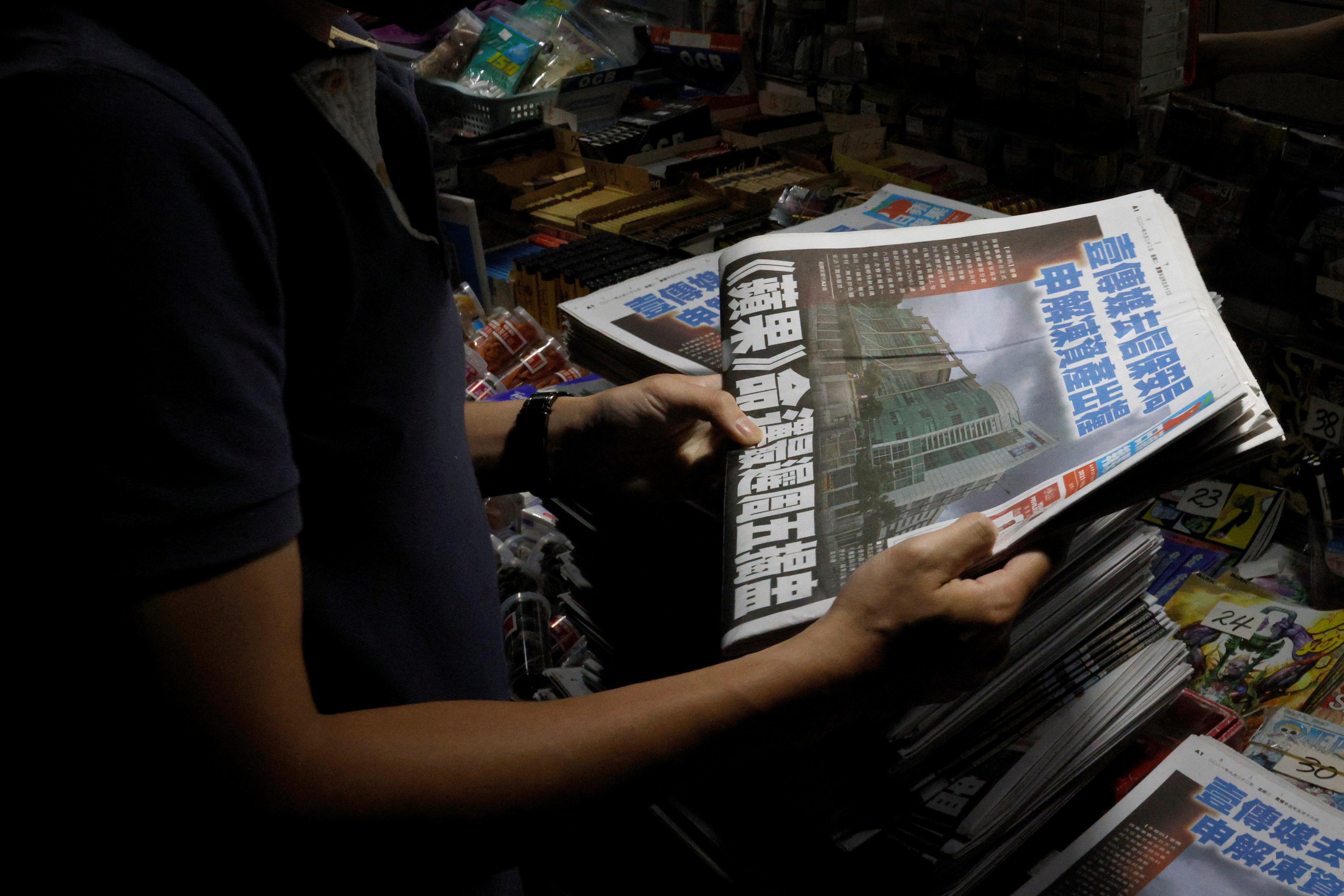 A man purchases a copy of the Apple Daily newspaper from a newspaper stall after it looked set to close for good by Saturday following police raids and the arrest of executives in Hong Kong, China June 22, 2021. REUTERS/Tyrone Siu