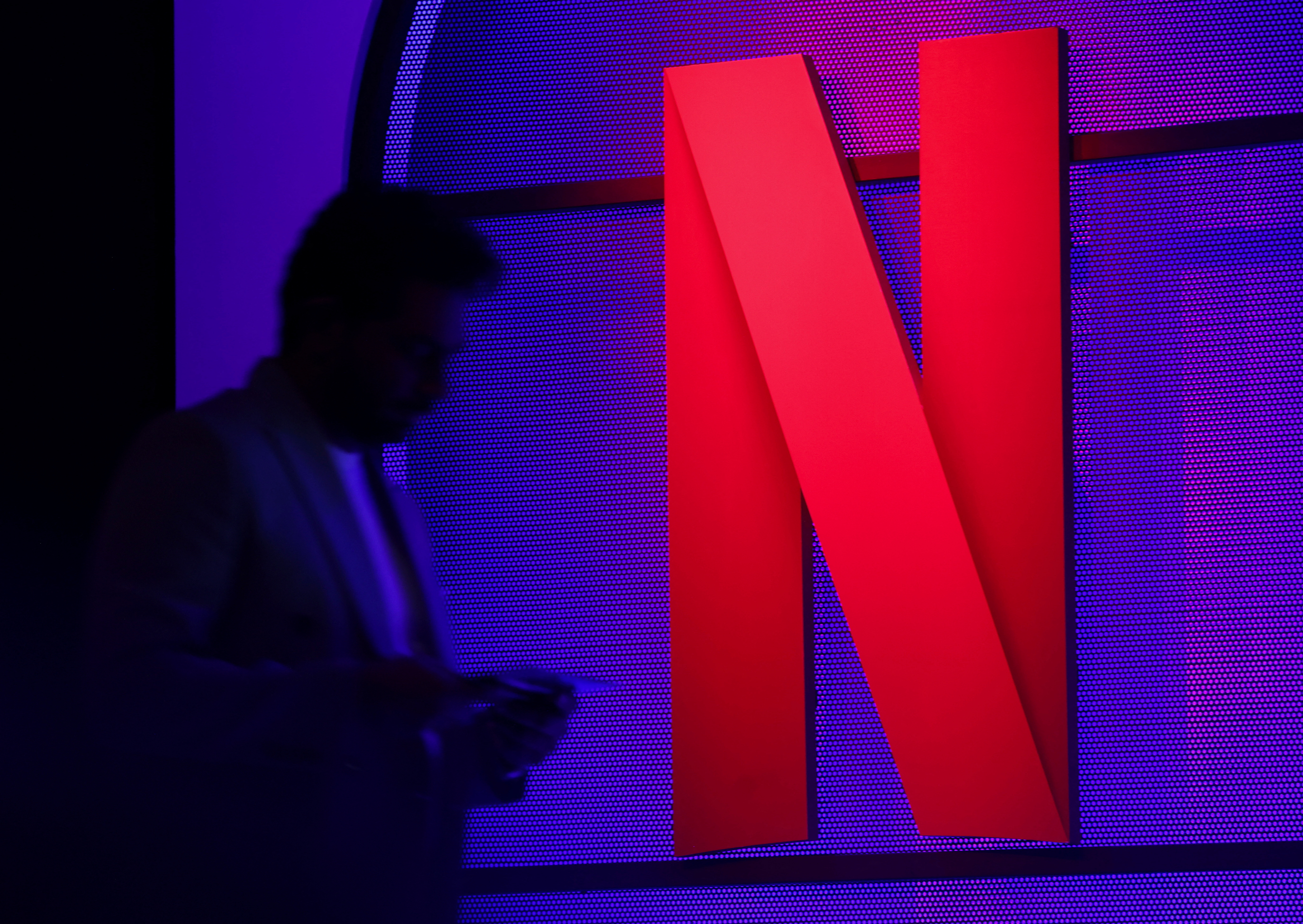 A man stands next to a logo of Netflix during an event in Mumbai